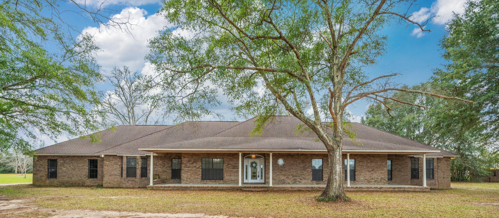 Discover the perfect blend of space, comfort, and country charm with this  4,800+ sq. ft. all-brick home situated on 8.75 acres of serene countryside. With approximately 8 acres of planted pecan trees and open pasture, this property is ideal for horses, livestock, or simply enjoying wide-open spaces. Step inside to find a massive 24x27 family room complete with a wet bar, making it the ultimate gathering spot or game room. The spacious living room offers a warm and inviting atmosphere, highlighted by a beautiful all-brick wood-burning fireplace, the perfect focal point for cozy evenings. Just beyond, a 29x11 sunroom overlooks the rear of the property, providing a peaceful retreat with stunning views. The 15x20 kitchen provides ample workspace for meal preparation and entertaining. An abundance of custom cabinets ensures plenty of storage for all your kitchen essentials, keeping everything organized and within reach. With its open layout and generous proportions, this kitchen is designed to be the centerpiece of the home; a place where memories are made and meals are crafted with ease. The primary suite is a true escape, featuring its own small wet bar and a luxurious 10x8 tiled master shower with multiple showerheads for a spa-like experience. Outside, a 15x11 detached building with electricity and a toilet offers endless possibilities: a charming she-shed, upscale kids' playhouse, private office, or man cave. Whether you're looking for peaceful country living, space for your animals, or a place to entertain, this property delivers it all!