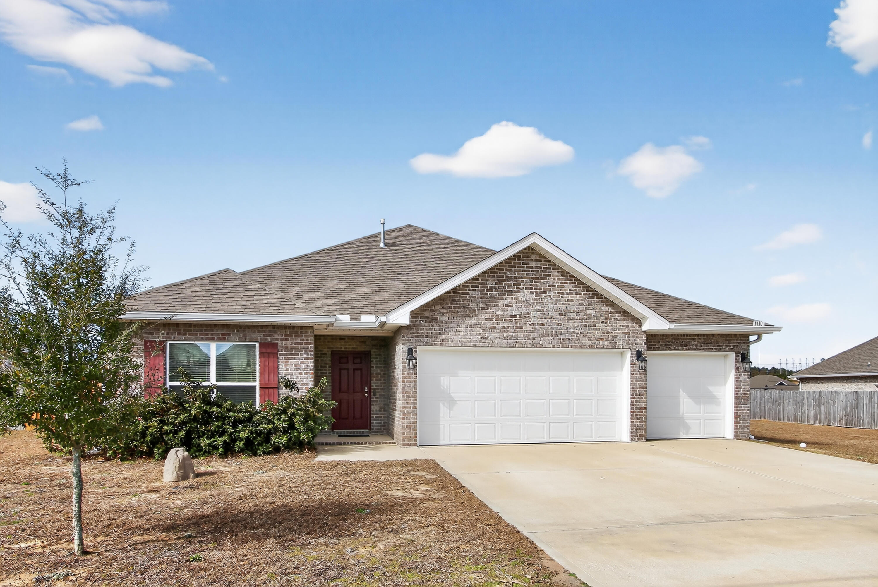 Stylish all-brick home awaits in Shoal River Landing, featuring the popular Destin floor plan. This stunning Craftsman-style residence offers four bedrooms and three full baths, along with a spacious three-car garage and a covered patio measuring approximately 12'5'' x 15', perfect for relaxing or entertaining. inside, you'll find a large breakfast nook complemented by a separate dining area, enhanced by tray ceilings with crown molding that add an elegant touch throughout the main living spaces. The kitchen and baths showcase beautiful granite countertops, stainless steel appliances, a dishwasher, island bar, and a convenient corner pantry, making the kitchen both functional and eye-catching. The spacious primary suite features a generous 5' x 12'4'' walk-in closet, double vanities, a  garden tub, and a large separate shower designed for comfort and relaxation. Luxury vinyl plank flooring runs throughout the home, with plush frieze carpet in the bedrooms for added warmth. Located in the desirable Patriot Ridge community, residents enjoy underground utilities, sidewalks, and a community pool, all in a convenient Crestview location. The fenced backyard offers privacy and includes a sprinkler system in the backyard only, adding ease of maintenance and completing this beautiful home that blends style, comfort, and everyday practicality.