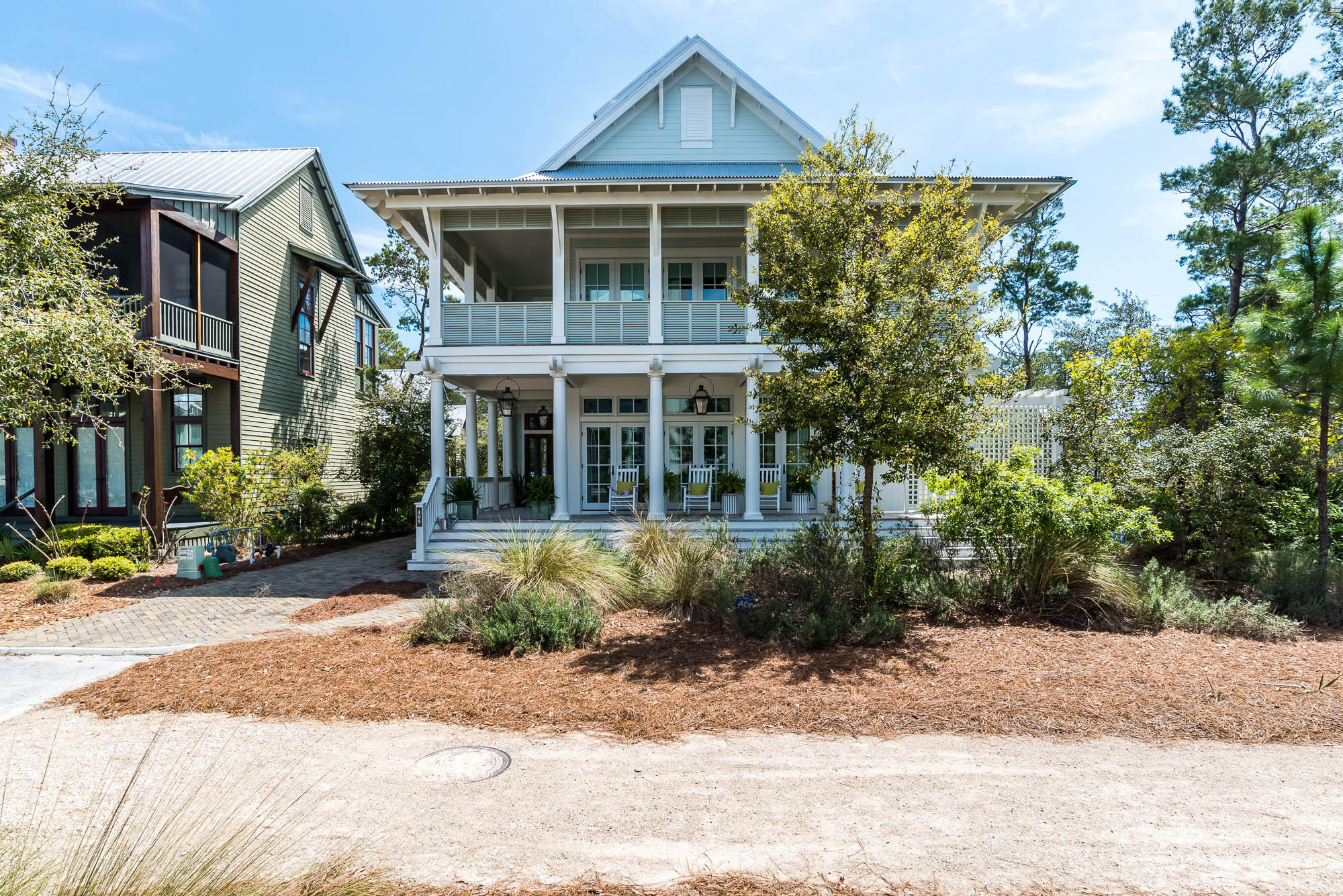 If you have an affinity for the Florida outdoors, you will fall head over heels for this four-story WaterColor Lakefront home with a two car garage and appointed carriage house. This home professionally decorated by Urban Grace Interiors is a MUST SEE! Brick paver pathways transport you to the perfect people watching perch in WaterColor; the homes expansive, wrap around front porch with stately white columns, inviting wood rockers and the glow of the gas lanterns warmly welcome you home. As you enter the home's French front door, you are greeted with white shiplap walls, soaring soft-blue shiplap ceilings, and natural light abound. The open floor plan great room features 7 sets of French doors with transom lighting leading out to the covered porch, a large dining room with a solid wood table, and a sprawling living room where memories are waiting to be made. A pass-through window opens to the heart of the home, the kitchen. With white granite counter tops, a perfectly located flat screen, and large center island with two farmhouse sinks; this kitchen is fit for a chef. Two Sub Zero fridges flank the pass-through, a Wolf gas range and hood, and perfectly disguised dishwashers complete the space effortlessly. Nano doors open this space to a screened in porch meant for gathering. You can also find a spacious pantry with ample storage and slide out shelving located directly off of the kitchen. Also off the kitchen is a conveniently located wet bar opening to the first floor office space and leading to the main floor guest suite featuring a walk-in closet with built-ins, full bath with glass shower, and dual vanities. Laundry rooms can be found on the first and second floors of this home. On the second floor, you will find a large bunk room with a living area, half bath and an attached screened-in porch with a ping pong table to entertain the kids and kids at heart. Off of the bunk room, you will find two additional guest suites with full baths, and the master bedroom, lined with double doors allowing in scores of natural light and complete with a private wrap around porch. The expansive master bath has dual vanities, a large glass shower with rainfall shower heads and a soaking tub, a private water closet and huge walk-in closet with built-ins. Stairs from the bunk room transport you to the third floor of this home where you can find a wet bar, desk space, a quaint home theater and convenient home gym. On the 4th floor, you are greeted with natural lighting, trundle beds and double doors leading to two separate private balconies with incredible views of WaterColor.