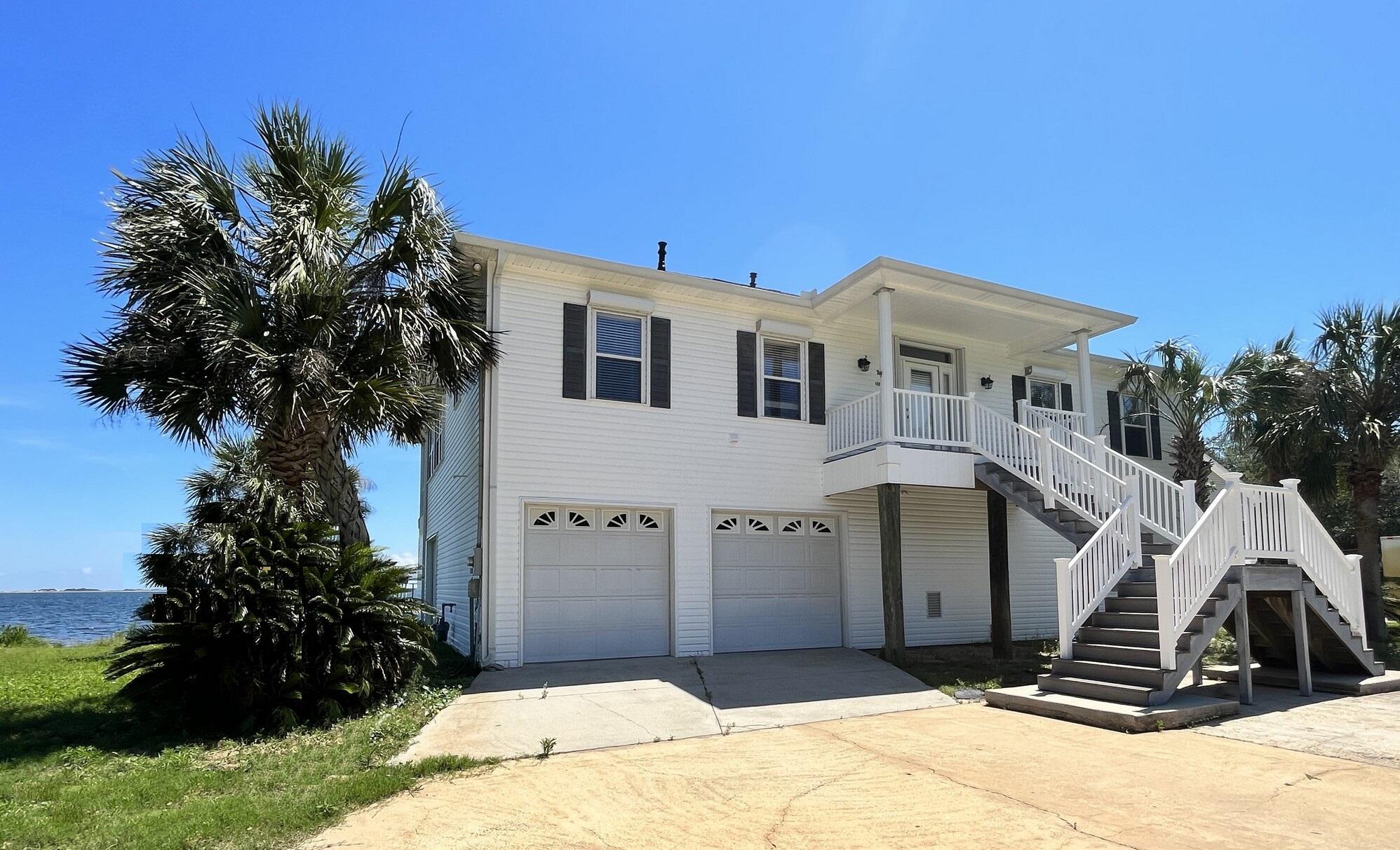 Sensational 180 degrees view of the Intercostal Waterway! The airy Entryway, Living Room, Dining Area and open Kitchen, Master Bedroom, Second Bedroom, and spacious covered back terrace - all with direct and unobstructed waterviews and offer views of pristine white sand natural preserve along Gulf of America! Coastal zone requires the house was constructed on piles. Gracious stairwells lead to the front patio and the back terrace. The living area features vaulted ceiling. Split floor plan sets master suit apart from the other two bedrooms and a bonus room. Tile throughout and in Master Bedroom carpet installed brand new.  All home living is located on upper floor whereas the entire ground floor is used for garage and large storage space set for workshop. The house has gutters, septic tank, and sprinkler system installed. Municipal sewer is available for connection. The waterfront terrace has clear view railing panels, screened in-porch and is complete with maintenance-free Trex decking. The house uses natural gas and has underground electric connection. It is also equipped with tankless water heater, energy-efficient 4-ton Trane HVAC, and a heat pump with gas back-up. The house is plumbed for natural gas generator. New roof provides ample warranty. Attic has been sprayed with insulating foam for energy efficiency. All windows and sliding doors are supplied with custom fitted Accordion Hurricane Shutters. The boat dock has power and water lines, needs repairs. No Association. Currently the house is unoccupied and move-in ready! Fits well for a single family with kids and pets or for working from home professionals, and suits for the retired couple. Or, the house is perfect to run the Air B&B!