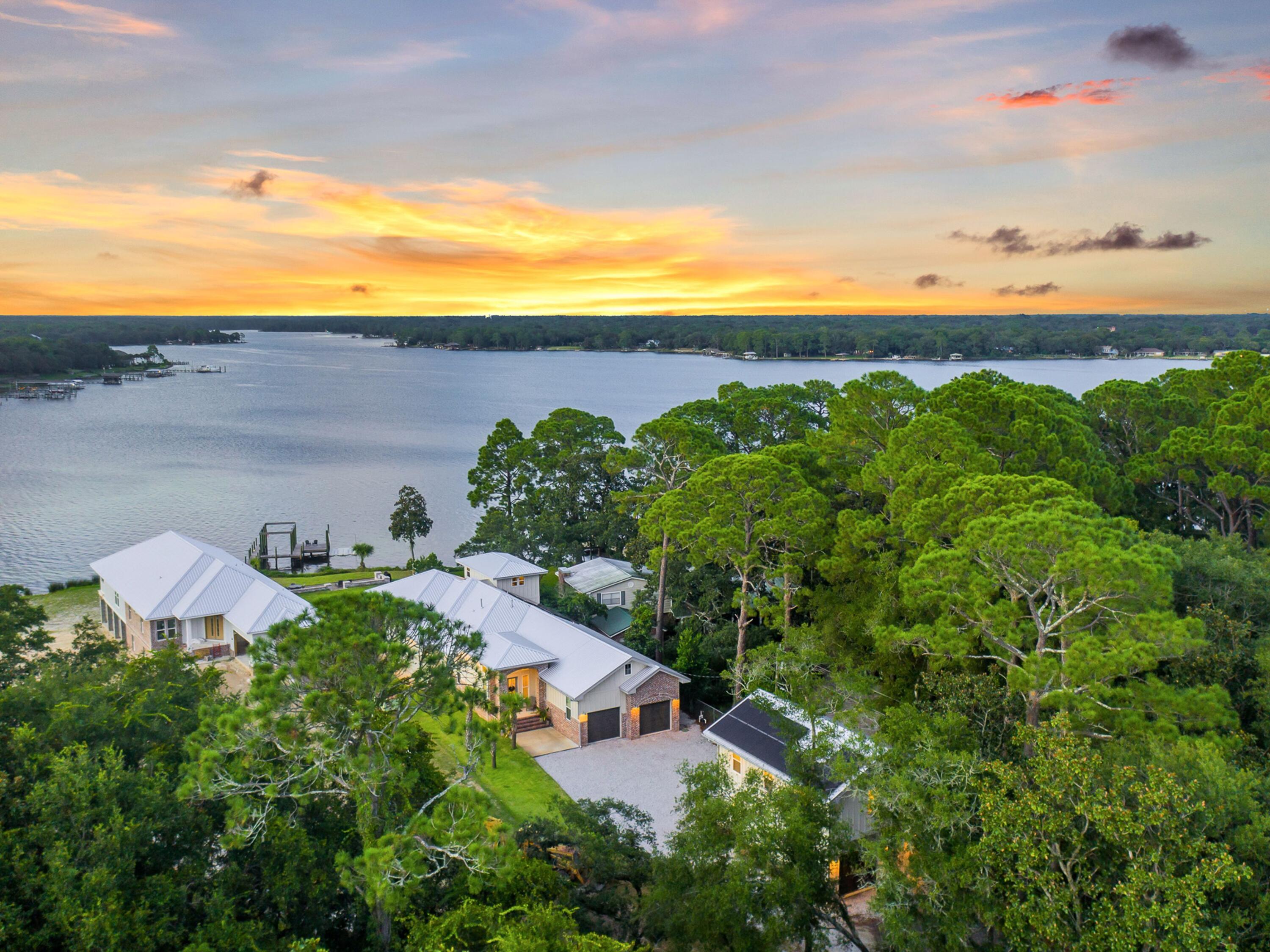 New construction opportunities are a rarity on the water in Fort Walton Beach and this nearly-new farmhouse-style build on 81 feet on Garnier Bayou is a must-see. Completed in 2020 as a builder's personal home, the 3,252-sq.-ft. main residence sits on more than a half-acre lot and features three bedrooms and two-and-a-half baths. A two-bedroom carriage house, dubbed the 'Beach Barn,' offers an additional 748 square feet of living space perfect for visiting family or guests. Inside the main home, delight in the open waterfront living on the first floor that seamlessly blends the living, dining and kitchen areas with wet bar to the spacious 40-by-15 patio that fronts the water. A second-floor pilothouse makes an ideal den or could be converted to a fourth bedroom. A 100-sq.-ft. heated and cooled bonus room on the first floor can be used to meet demanding storage needs, as a home office or play room. Wide-plank wood flooring, shiplap accents, antique French doors, reclaimed brick and quartz countertops throughout are hallmarks of this home, which also features a Frigidaire Gallery appliance package, walk-in pantry, custom paver patio and more than $50,000 in site preparation. Outfitted with only the best fixtures and finishes, the builder took careful steps to incorporate energy-saving measures throughout including 2-by-6 wood frame construction, foam insulation, radiant insulation panels under a metal roof, solar packages and impact-resistant windows and garage doors. The main home includes an attached two-car garage while the detached carriage house has its own 748-sq.-ft. heated and cooled 'drive-thru' garage with utility sink that would make an ideal recreation room or home gym. The property boasts its own outdoor oasis including a fire pit, water mitigation structure, and private dock complete with freshwater line and electricity with boat slip and floating jet ski launch. There is also room for a pool. A public boat launch is accessible just 400 feet away. This home is centrally located near Hurlburt Field and Eglin Air Force Bases as well as Fort Walton Beach Medical Center and nearby middle and high schools. Set back from the road in a private and quiet location with native wildlife like ospreys, pelicans and bald eagles, you'll be satisfied knowing you're minutes from the action but in a tranquil world all your own.