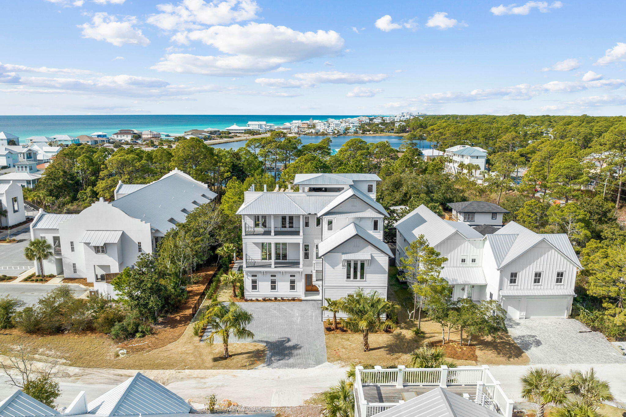 Recently completed by the highly regarded Cogent Building Group, 54 Martha's Lane is a striking example of modern coastal design, balancing refined craftsmanship with effortless livability. Thoughtfully designed to maximize space, light, and comfort, this three-level home offers a seamless blend of private retreats and open gathering spaces, culminating in a rooftop terrace with panoramic Gulf and Coastal Dune Lake views. Every detail has been carefully curated to enhance the coastal lifestyle, with high-end finishes, premium amenities, and a layout that caters to both relaxation and entertaining. Upon entry, the first floor is designed for comfort and ease, featuring a media lounge and bar area equipped with a sink, mini fridge, and ice makeran ideal space to unwind. Just beyond, the outdoor living area is a private retreat, complete with a heated pool and spa, firepit, and a fenced backyard with lush green space. A screened porch offers additional al fresco dining, a TV, and a cozy seating area, while the summer kitchen, outfitted with a grilling station, bar seating, fridge, and ice maker, makes entertaining effortless. Two king guest suites with ensuite baths, a well-appointed bunk room, a mudroom with garage access, and a full laundry room complete this level.
The second floor serves as the heart of the home, where expansive windows and refined finishes define the main living space. The chef's kitchen is designed for both form and function, featuring an oversized island with seating for seven and top-tier Thermador appliances, including a dual-oven range, oversized refrigerator, dishwasher, and convection microwave. A wet bar with a wine fridge, sink, and ice maker enhances the space, flowing seamlessly into a dining area with a custom table for ten and a welcoming living room with plush seating, a fireplace, and curated design elements. Glass doors open to a balcony overlooking the pool, offering an outdoor dining space and lounge area to take in the coastal breeze. A king guest suite with an ensuite bath and a conveniently placed powder room complete this level.

The third floor is designed for privacy and retreat, featuring a secondary media lounge with a large sectional and balcony access, as well as a wet/coffee bar with a sink and wine fridge. Four king guest suitesthree with ensuite bathsprovide comfortable accommodations, while a dedicated bunk area with twin-over-twin built-ins shares a well-appointed bath. An additional laundry facility adds convenience for extended stays.

The rooftop terrace is a standout feature, offering unobstructed Gulf and Coastal Dune Lake views. Designed as an extension of the home's living space, it features a spacious sectional, an al fresco dining table, and four sun loungers, all complemented by a wet bar with a TV, sink, mini fridge, and ice maker. Whether enjoying a quiet morning coffee or an evening gathering with friends, this elevated retreat provides an unmatched setting to take in the surrounding beauty.

With an ideal balance of thoughtful design and luxurious comfort, 54 Martha's Lane is a home that captures the essence of coastal living. Built to offer both a retreat from and a connection to its surroundings, this newly completed residence is an exceptional opportunity to experience the best of 30A.

Reach out to us today for cost-to-own-figures & rental projections.