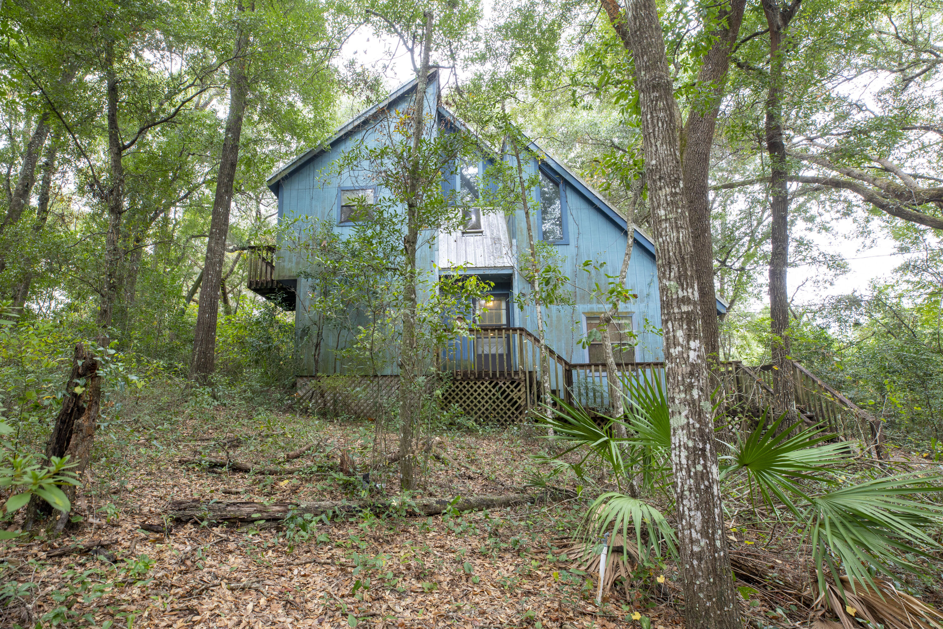 This may not be for you, but this home is a fabulous investment opportunity!  This home offers privacy on a wooded double lot.  There are 3 bedrooms and 2 full bathrooms.  There is a unique sunk-in living room that is accentuated by a beautiful, peaked wood ceiling.  This home takes advantage of the private lot with several upper and lower decks including a 20 x 12 deck off of one of the 2nd story bedrooms. Imagine what this home would be like with some updates.  An amazing opportunity waits for a buyer with a conventional loan or cash willing to do the updates or this home is prime for a renovation and resell.  Just 1/2 mile to Turkey Creek Park.  Short drive to Eglin AFB.  The metal roof with skylight was installed in 2010. The exterior siding has some wood rot near the ground and the wooden decks are in need of repair.  Do not walk on decks.  All information is believed to be accurate, however anything deemed important should be verified by the buyer.  This home will not qualify for a VA or FHA loan.