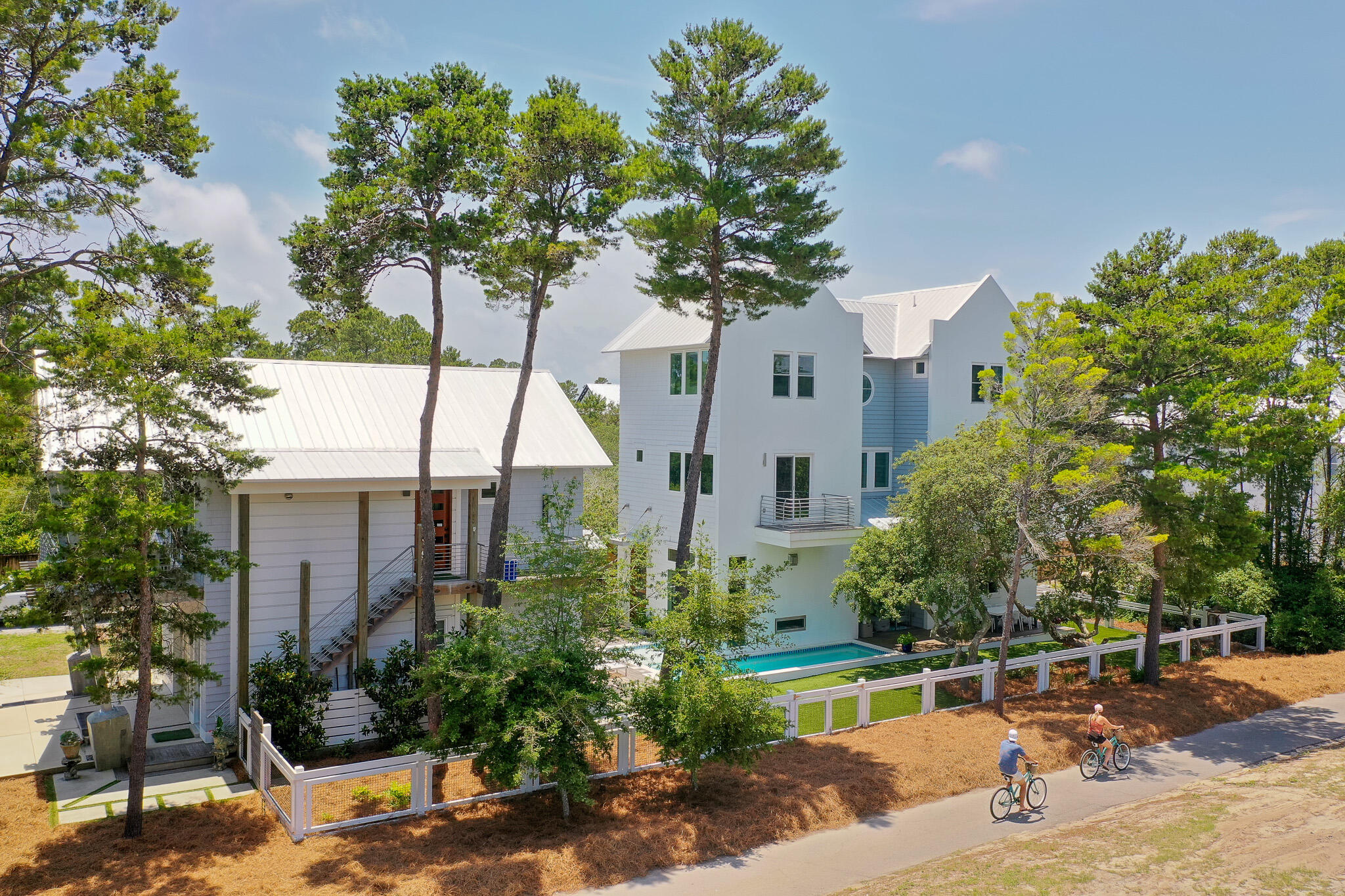Welcome to 16 S Lake Drive—Where Elevated Design Meets Everyday Ease.

Tucked just moments from the coast, this thoughtfully designed retreat blends custom craftsmanship with everyday comfort in a way few properties can. Designed and built by Minchew, every detail of this home tells a story—from the rich blend of red oak, white oak, and hickory flooring to the rough-sawn oak ceilings that warm the main living spaces with understated elegance. The main home spans approximately 3,350 square feet and offers four bedrooms, a flex gym room, and a third-floor primary suite that feels like a private penthouse escape. Wake up to a morning bar just outside your door, enjoy the convenience of an in-suite washer and dryer, and unwind by the dual-sided fireplace that connects the indoors with the serene poolside setting outside. A dedicated dog wash station, reverse osmosis water filtration at both bar sinks, and GE Café appliances reflect a level of thoughtful living rarely found.

The separate carriage house offers an additional 796 square feet of guest-ready luxury, complete with a full kitchen, two bathrooms, island seating, and its own oversized porchperfect for soaking in the breeze or welcoming extended guests. 

Artful touches and purposeful design continue throughout: vaulted ceilings, built-in desk workspace, custom tile and lighting selections, and a garage that has been reimagined as an office space, complete with its own mini-split AC and bath. With landscape lighting, turf grass, and a driveway large enough for six or more cars, the home is ideal for gatheringand zoned to support it.

This is more than a house. This is a backdrop for your next chapter.