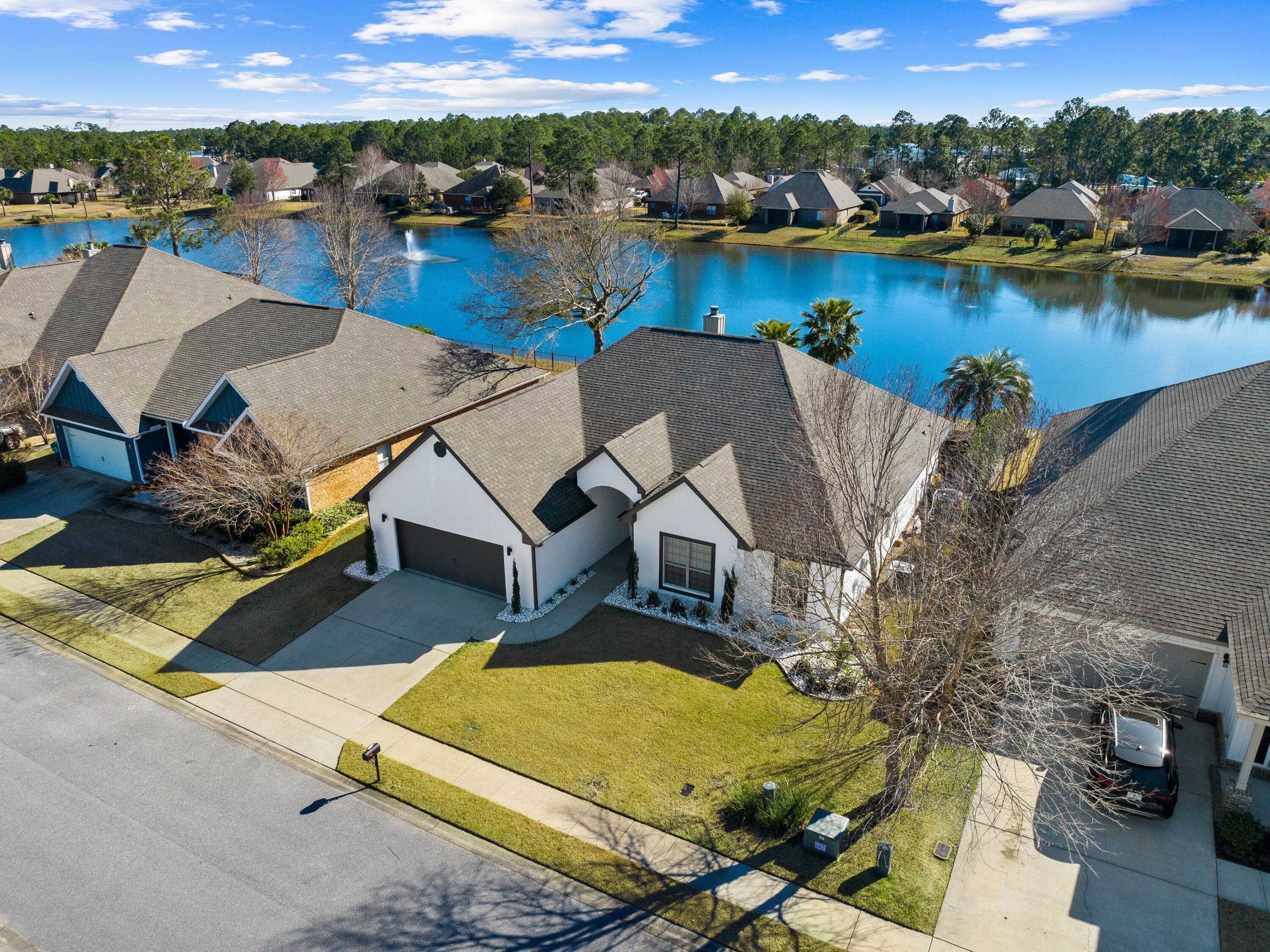 Close to Blue Mountain Beach, this amazing updated home is brimming with design features and is move-in ready. Enviably located in a peaceful neighborhood, this desirable residence overlooks a lake and wildlife. The private backyard includes a heated and cooled pool, lush landscaping and a fountain. It's ideal as a full-time residence for first-time buyers, retirees or those looking to enjoy a coastal lifestyle. Laid out all on one level, the home has four beds, two full baths, a cloakroom and an attached two-car garage. Bonus features worth mentioning include a  built-in desk area in the fourth bedroom and a spacious master suite with a sitting area, a large walk-in closet and a sliding barn door to the master bath.  Hardwood flooring seamlessly connects the well-lit dining and living areas. A cozy fireplace adds a focal point. Soaring vaulted ceilings are highlighted with updated lighting and deep crown molding. An archway leads into a bonus space suitable for use as an office, media or game room. The updated kitchen has many natural elements including a white brick-faced peninsula bar and beautiful quartz countertops. Keen cooks will find a full array of stainless steel appliances at their fingertips along with ample storage. Outdoor living is a delight with a covered patio where you can relax and enjoy the peaceful lake views. The fenced backyard is ideal for keeping kids and pets secure as well as providing privacy when entertaining. The covered lanai looks out across the paved terrace to the pool with tanning shelf and the lake beyond. Close to many restaurants, shops and amenities, this pristine home is also within easy reach of beautiful beaches, hiking trails and outdoor recreation at Topsail Hill Preserve and Point Washington State Forest.