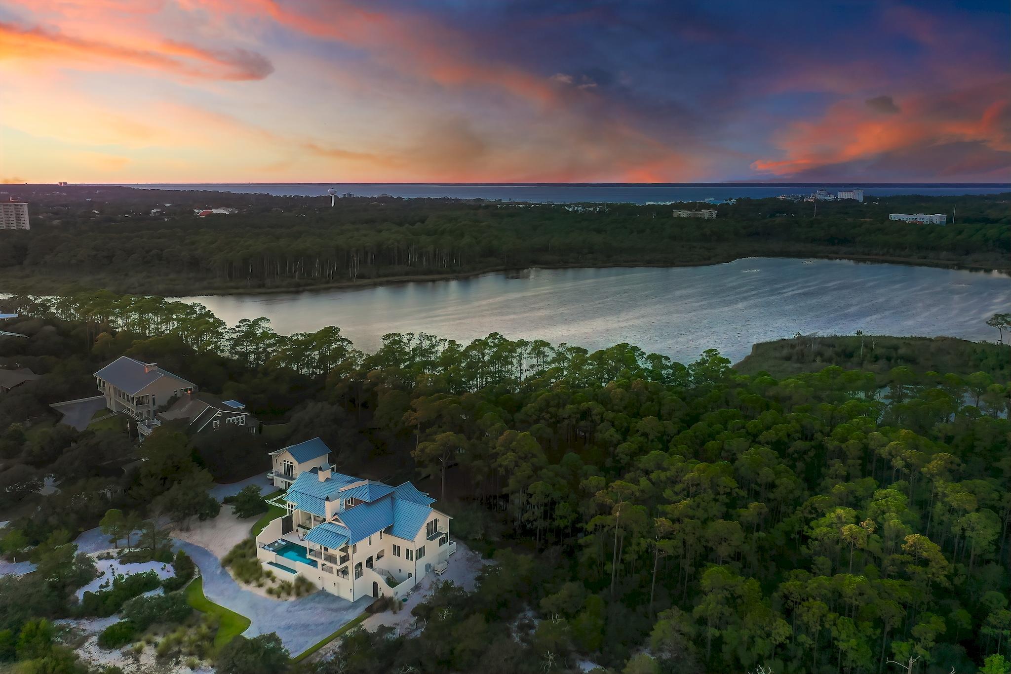 Imagine a home so sheltered by nature that a mother deer and her fawn amble slowly by the window headed to the rare coastal dune lake that serves as the northern boundary. Gaze from the open-air balcony across seemingly endless white sand dunes that wind to the shimmering emerald waters of the Gulf of Mexico. Truly a one-of-a-kind opportunity in Northwest Florida, 285 Twisted Pine Trail offers all of this and much more, all located within minutes of first class dining and entertainment.
 
Situated on just under three acres in the gated sanctuary of Four Mile Village, this property is also bordered by Topsail Hill Preserve State Park offering an incredible sense of seclusion. An exquisite Geoff Chick design expertly constructed in 2017 features panoramic views of Fuller Lake and the Gulf of Mexico throughout. The property includes almost 300' of frontage on the lake with a private dock.

From handmade lighting imported from Murano, Italy, to rough-hewn Louisiana cypress floors, every detail of this home has been carefully curated to create a masterpiece retreat. An expansive open-concept living and dining area with a gourmet kitchen is ideal for everyday life while added conveniences such as a wet bar, full butler's kitchen, and wine cellar allow for seamless entertaining. European doors fully retract to unite the living area with the outdoor entertaining spaces on both sides of the home including covered porches, open decks, and an infinity-edge swimming pool and spa.

No dream or desire is absent in this property with each room offering a unique experience. Abundant windows provide picturesque views of the gulf to the south and the lake to the north. Soaring vaulted ceilings with gorgeous exposed beams and a striking double sided fireplace are highlights of the living area. The kitchen offers an expansive center island crafted from quartzite with a suite of Thermador appliances. A first floor study includes pecky cypress built-ins and floor-to-ceiling windows.
 
The master suite is a true retreat with a fireplace, private balcony, and an expansive master closet with custom built-ins. The master bath shower and soaker tub both overlook the gulf while the large vanity includes a seating space. All bedroom suites feature either gulf or lake views while each bathroom is characterized by intricate custom tile work with no two alike. A third level bunk room includes a morning bar for added convenience, and an elevator services all three levels of the home.

The detached carriage home includes a luxe first level game room with wet bar and golf cart garage. Upstairs, find a large light-filled space with stunning views, built-in bunks, a morning bar and a full bathroom.

Homeowners in Four Mile Village enjoy the unique benefit of a pristine beach front preserve that includes 230 acres of coastal woodlands, a 40 acre coastal dune lake, and 2000 feet of private shoreline on the Gulf of Mexico.  Four Mile Village is located across from the Sandestin Golf and Beach Resort with shopping, dining, championship golf courses, world class tennis facilities, swimming pools, fitness center and a 113-slip marina.