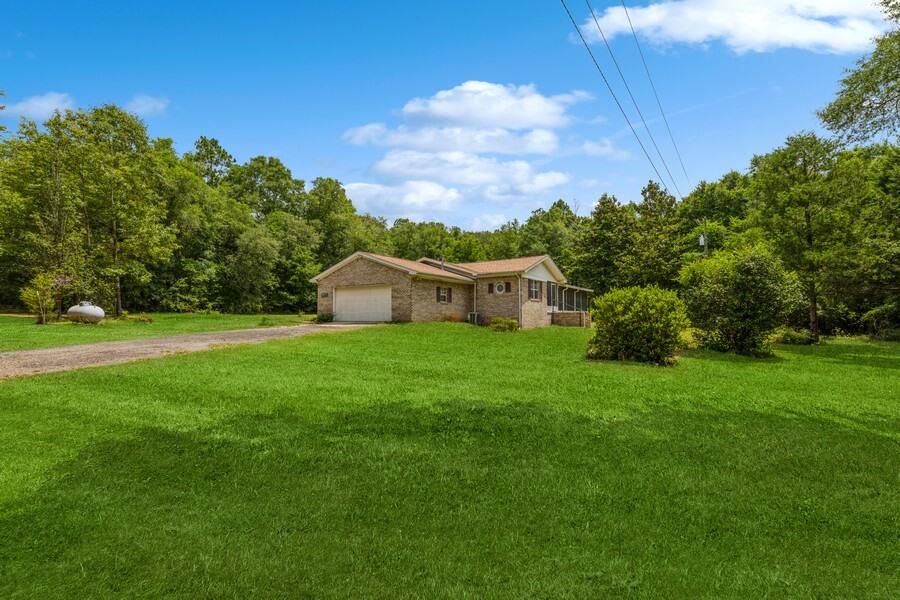Are you looking for a home that offers privacy and seclusion? Situated on 4.32 acres just minutes from the back gate of Whiting Field, this 1440 SF Brick home might be just what you are looking for. From the screened front porch, step into the Foyer and to your left is a large Living Room with newer carpet. Continue to the Dining Area, which spills into the Kitchen and is a great gathering area, while dinner is being prepared. Down the hallway to your right is the hall bath with updated vanity. Master Bedroom has full bath with updated vanity. Two other bedrooms are on this wing of the home. Laundry closet and Water Heater inside home. New roof 6/23. 2-car attached Garage. Outside you will find a detached 24 X 30 workshop with power. Lots of trees and garden areas. You will love exploring this special property. This unique home is located just minutes to Milton City Limits. Lots of parks and water activities nearby. Call today to view.