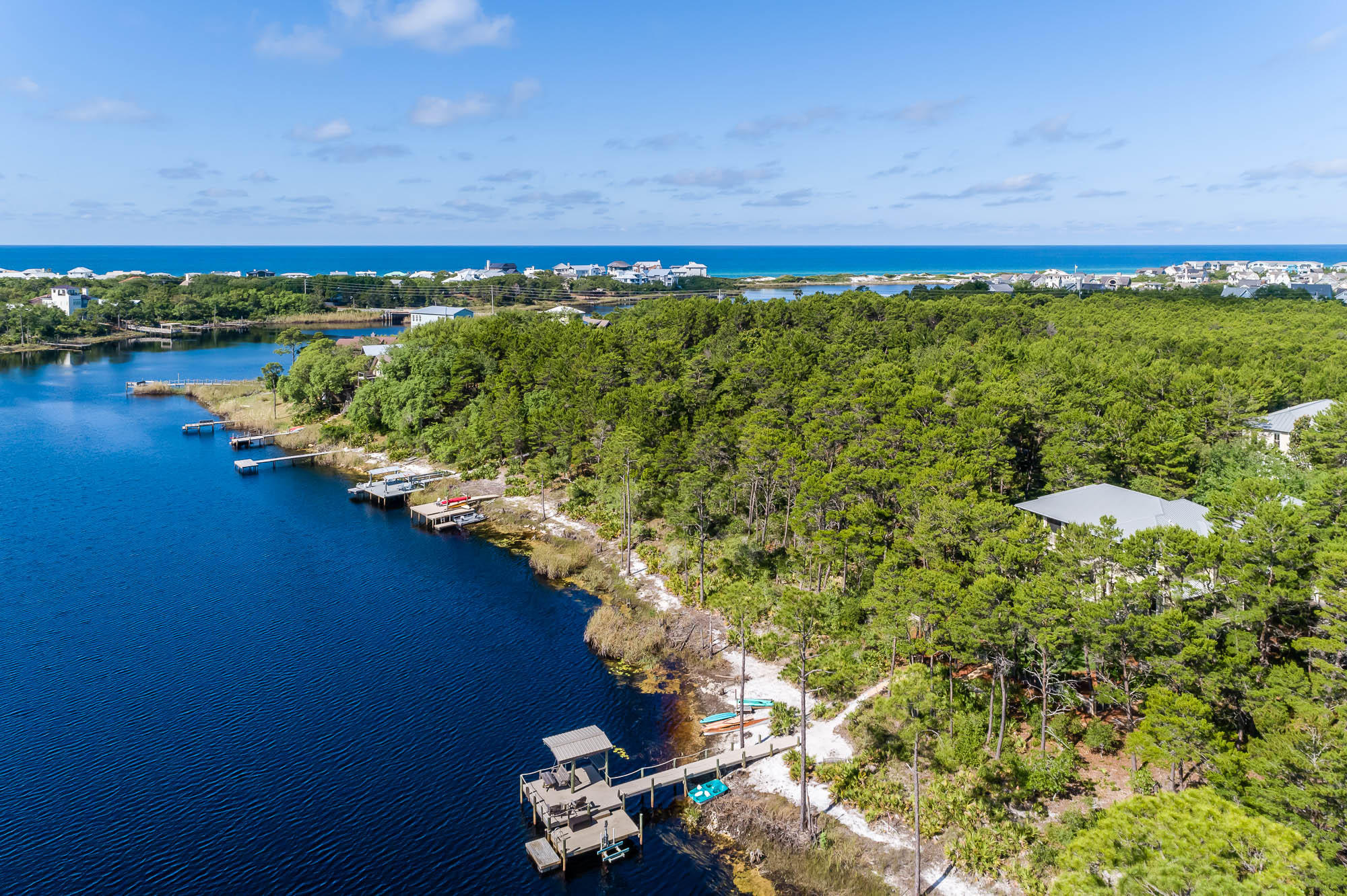 Live the lake life on a rare coastal dune lake, within the secluded gated community of The Landing at Camp Creek. Located on 30A's east end, directly across from Watersound Beach and just 2.3 miles west of Alys Beach. Seize the chance to enjoy picturesque vistas daily on this rare, coastal dune lake of Camp Creek Lake. No short-term rentals are permitted, adding to the quiet privacy. This well-appointed, lakefront residence with carriage house embraces a unique ambiance where coastal nature abounds. It boasts expansive porch views and is surrounded by natural preserves. The large site banks down to your own private dock and natural beach, spanning 68 feet of natural lake frontage and ... provides the perfect place to paddle over to the Gulf of Mexico or soak in the sunsets and stillness from your dock. The large rear porch is perfect for entertaining, or simply relaxing and taking in scenery. Enjoy the sound of the waves from the Gulf as it echoes off of Camp Creek Lake. Wake up to beautiful sunrises each morning, impressive views to be enjoyed from your bed in the second level master suite. Four of the guest rooms in the main house overlook the lake and open to screened porches. The residence also offer a detached carriage house, over a 2-car garage, providing you and your guests with much needed space and privacy. The carriage house offers a full kitchen, comfortable living room, laundry and enclosed bedroom with en suite bath. The high quality craftsmanship and design excellence of this offering do not go unnoticed. This retreat includes finishes and amenities such as a gas range, wood beamed flanked 10 foot ceilings, screened porch, travertine tile & heart of pine floors. This coastal home is also upgraded with a gas stone fireplace, metal Bahamian hurricane shutters, outdoor spa, spacious dock with a jet ski lift and is professionally landscaped. This serene location is an easy bike ride to The Hub and is just minutes to everything 30A has to offer!