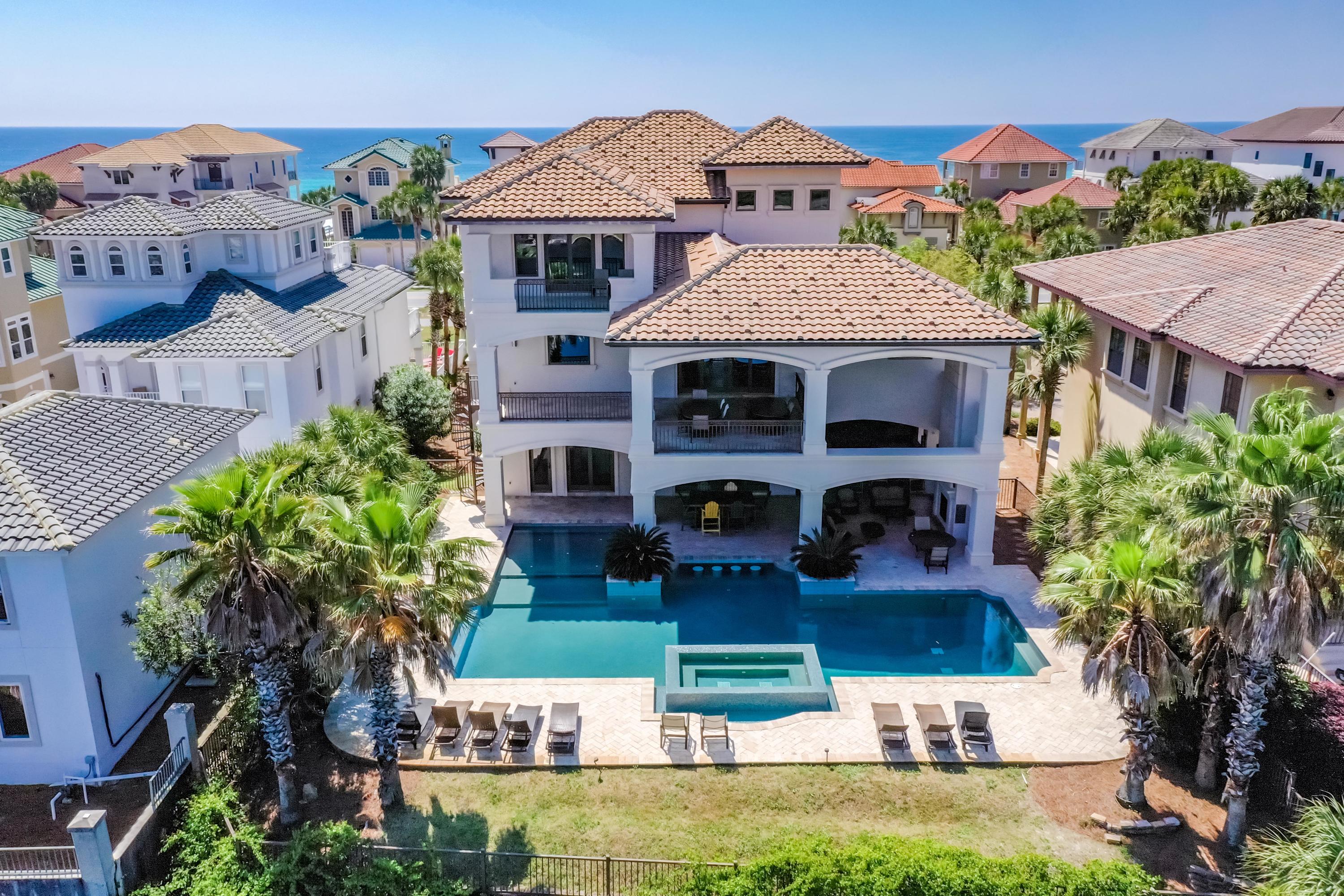 Fantastic 3+ story beach home, on a lakefront lot, just steps from the beautiful white sand beaches and enjoying gorgeous Gulf views!
Extra high ceilings, quality materials, excellent craftsmanship, and beautiful fixtures complement the well-designed floorplan, which offers 7 bedrooms (including multiple master bedrooms and suites), 3 bunk rooms (8 total bunks), and 8.5 baths while providing a comfortable degree of privacy. Ideal for entertaining, the common areas include a stunning gathering space on the main floor for hosting large parties indoors, featuring a vaulted pecky cypress ceiling in the dining area, a huge kitchen island and plenty of storage and prep space, a large living area with fireplace, and decks on both ends. Or head outdoors for the summer kitchen, fireplace, covered patio area, large pool/hot tub and lake views. The ground floor also includes a game room and mini kitchen. Numerous balconies and a rooftop deck enhance the enjoyment of the stunning setting! An elevator allows accessibility for all. Additional features include 2 garages, sound system, media wiring, and much more!
  
The residence commands a strong rental income or would make a very special family legacy home--or both!