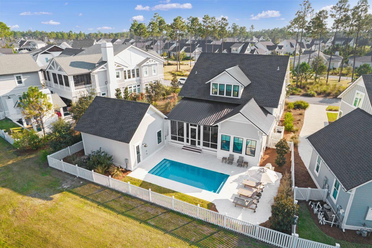 Located on one of the most coveted streets in Origins, this custom home by Arkon is within the exclusive WaterSound Origins community. Completed in 2021, this nearly-new beach home comes with its own heated saltwater pool, outdoor shower and sun deck on a picturesque and tranquil pond. The full-width front porch is a quiet shady spot for enjoying a book or socializing with family and friends at sunset. Inside, beautiful hardwood flooring and shiplap walls reflect the surrounding natural environment that Origins is known for. The bright and airy living room has ample space for entertaining. It flows naturally from the sitting area around the fireplace to the open dining area and kitchen. Three sets of double doors open directly onto the large screened porch, allowing pine-scented breezes to waft gently indoors. The open kitchen has pristine white Ceasarstone quartz countertops with a generous breakfast bar. It is fully fitted with stainless appliances including a French door refrigerator with a freezer drawer. A tile backsplash and open shelving add subtle design touches to this practical space. There's additional storage in the adjoining pantry and laundry room and a convenient side door leading outside. The master wing has a spa bath with his and hers closets and a show stopping view of the pool and pond behind. In addition to the 1st floor master, there is an additional guest suite with en suite bath. Upstairs offers two additional guest suites both with large bonus areas for sitting and relaxing or watching TV. In addition to the four generous bedrooms, this two-story home has multiple additional spaces. There's a private office on the first floor and a media/entertainment room on the second floor. The oversized two-car garage has ample space for a golf cart and just a short putt from the door you'll find Origins Golf Club and  NatureWalk. This home offers privacy with an idyllic community park in the front and the small pond just behind. Residents enjoy access to the Village Commons pool, fitness center and Lake Powell dock as part of the amenity fee. Rosemary Beach is within easy reach, offering delightful shopping and dining experiences along with regular outdoor entertainment.