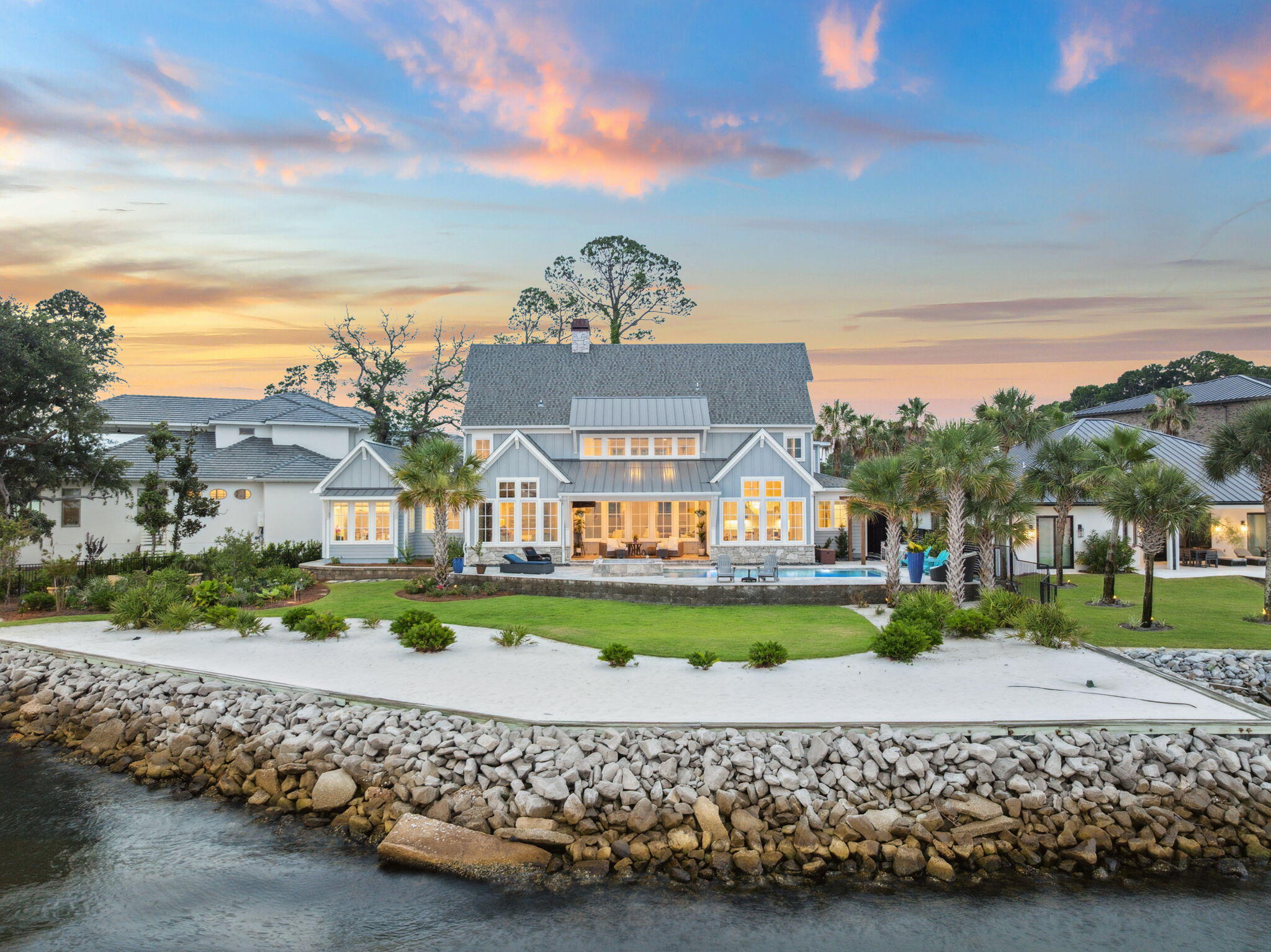 37 Driftwood Court is a Watersound-inspired mansion tucked in the center of a quiet, five-home cul-de-sac and offers the kind of privacy that's hard to come by in this area - while still being just minutes from Grand Boulevard, Topsail State Park, and Scenic Highway 30A. The home greets you with a floorplan that opens up immediately: 20-foot ceilings in the great room are framed by floor-to-ceiling windows that flood the home with natural light, waterviews, and sunsets along the Choctawhachee Bay. 
The layout was made for hosting and the uniquely wide lot creates a floor plan that sprawls & gives each space a sense definition & flow. The open-concept main level comfortably accommodates up to 40 guests, and the kitchen sits right at the heart of it all, as any good kitchen should.