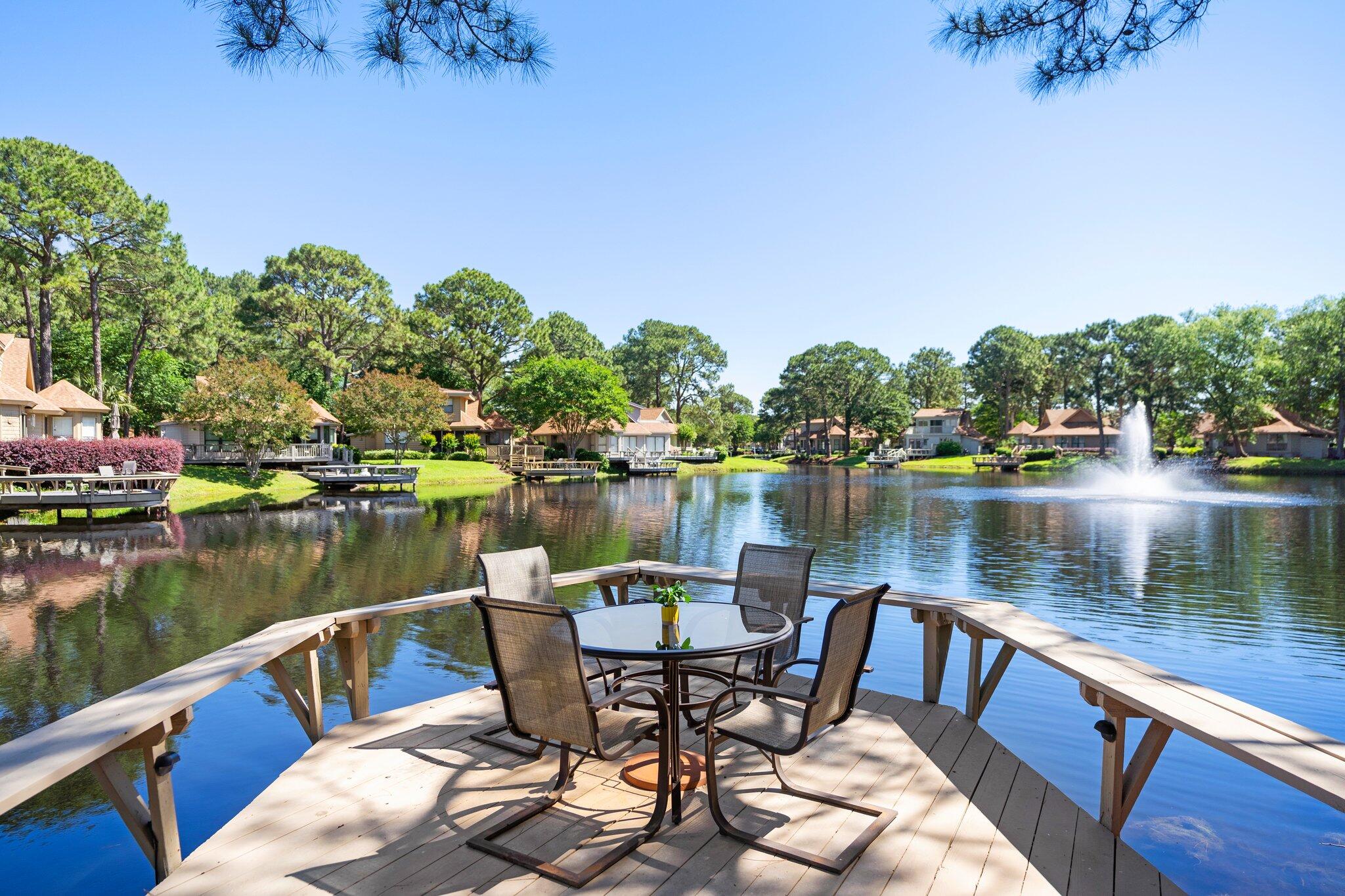 RESORT LIFE AT ITS BEST!! PRICE REDUCED FOT THIS SLICE OF PARADISE!
Outstanding opportunity to own one of the adorable Fairway's free standing cottages! If you have been looking for fabulous water views, privacy, expansive outdoor space, ONE LEVEL and no shared walls! This  cozy cottage is  surrounded by mature trees, 2 fountains and boasts a screened-in porch, oversized outdoor deck overlooking lake and fountains PLUS a dock on the lake! New roof in 2024, updated kitchen and baths,offered fully furnished and ready to enjoy or rent. Golf cart parking/charging right out front and a HUGE attached storage shed included. The newly constructed community pool is just down the road!