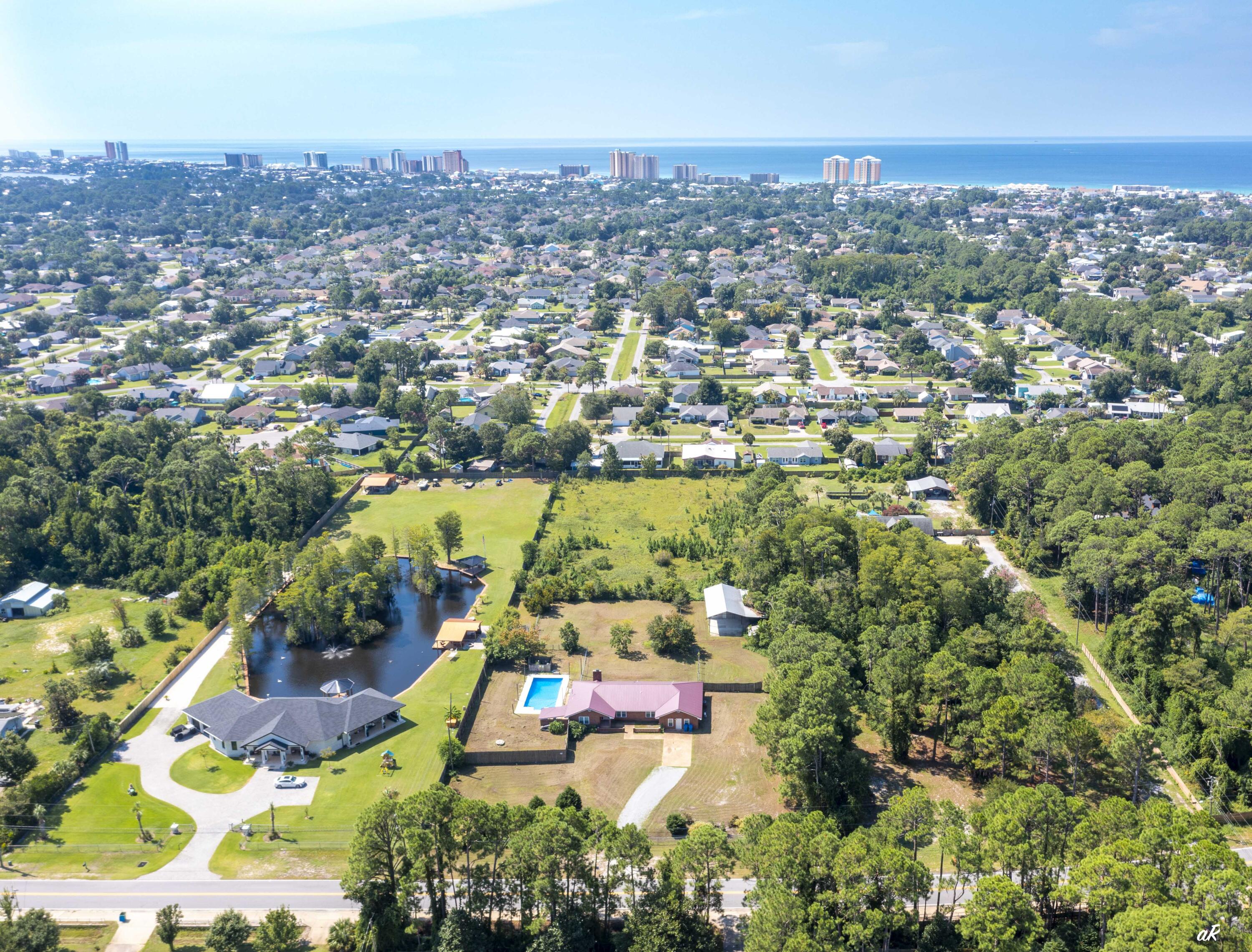 Looking for a RARE opportunity to own acreage on Panama City Beach? Well, come on and bring your horses! This ranch style home sits on 2.88 acres of fenced-in land with a large pole barn that includes an air-conditioned office area. This property is conveniently located between Saint Andrews Bay and the Gulf of Mexico, Near Thomas Drive and the Navy base. This home is being sold Fully Furnished with an acceptable offer! Recent upgrades to the home include a new metal roof in 2023, all new gravel driveway, granite countertops, & new appliances. This home offers a wide entry way into the open living room with a wood burning fireplace and sliding glass doors to the backyard. The master bedroom has beamed cathedral ceilings, a walk-in closet and en suite bathroom with jetted tub. There are an additional 1344 sqft of covered storage. The home is not in a flood zone and completely fenced to provide privacy and seclusion. The opportunity to own a ranch style home, with a workshop, and almost 3 acres of land on the beach doesn't come available very often. This is currently the ONLY property of its kind available on Laird St. So, don't wait and schedule a showing today!