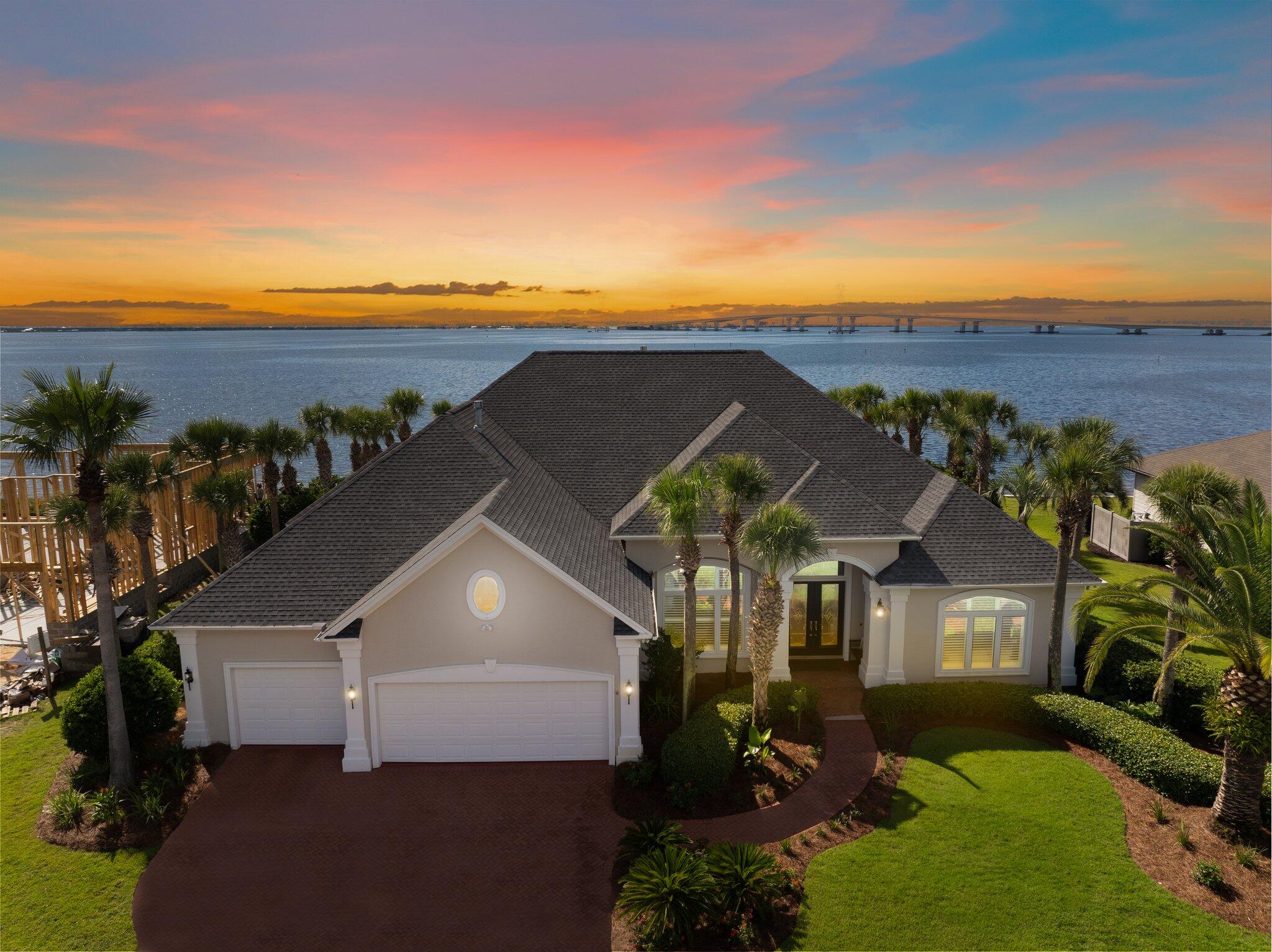 Experience unparalleled luxury in this pristine single story home with 4-bedroom and 3.5 bathrooms, overlooking the serene St. Andrews Bay. Spanning over 3,880 square feet of refined elegance, this property boasts two master suites and is set on over 1/3 acre with 108 feet of prime bay frontage. This rare find comes with a deeded 40-foot boat slip and a dazzling saltwater pool, this residence is truly move-in ready awaiting for its new owner. Step inside to be greeted by gorgeous chandeliers, breathtaking panoramic views, and exquisite travertine tile throughout. The spacious great room features a stunning John-Richard chandelier, double-sided gas fireplace adorned with Medusa stone, and a charming entertainment center. The gourmet kitchen is a chef's dream, complete with an island,  breakfast bar, wine fridge, Sub-Zero refrigerator, new Viking 48'' gas range, new Viking dishwasher, Viking microwave, Currey & Company lighting, and a breakfast area with custom remote control shades. A separate dining room is conveniently located off the kitchen and great room. Both master bedrooms offer spectacular bay views. The primary master suite includes a tray ceiling, gorgeous John-Richard chandeliers, large walk-in closet, double vanities, a walk-in shower, and a soaking tub. The second master bedroom is equipped with a kitchenette and walk-in closet. The third bedroom is spacious with a large walk-in closet. Freshly installed carpet graces all bedrooms, and the fourth room can serve as an office or additional bedroom. The expansive laundry room features an Electrolux washer and dryer, a new Fisher & Paykel refrigerator, built-in desk, and large built-in pantry. A three-car garage provides ample storage. Throughout the home, you'll find gorgeous custom draperies and plantation shutters. Your backyard oasis includes a pergola, a saltwater pool overlooking the bay, an outdoor fire pit, and custom dolphin sculptures by Jimmy Warren. The pool has been updated with a new heater and was resurfaced last fall. A gas line runs to the back patio, ready for an outdoor kitchen expansion. The deeded 40-foot boat slip is just a block away at Dolphin Bay's Private Marina- Harborage Yacht Club. Complete with electric, water, and a boat box. An adjacent boat ramp adds convenience. Dolphin Bay is conveniently located in the heart of Bay County on the East end of Panama City Beach, convenient to hop over the bridge to Panama City, or take Thomas Drive to ''The World's Most Beautiful Beaches,'' or head West to Pier Park, 30A and Destin. This is a gated community and offers tennis courts as well. Enhancements to this home include two new A/C units, a Navien tankless water heater, Marvin TruStile solid doors with Emtek hardware, new windows, new high-end lighting, custom built-in closets + pantries, new bathroom fixtures, a whole-house sound system, and exterior painting with elastomeric. New well pump for irrigation. Two new propane tanks installed to run the gas fireplace, viking range and water heater. Beautiful lush landscaping completes this exquisite property. This move-in-ready home comes with no city tax and low HOA fees. Don't waitschedule your private showing today and make this dream home yours!