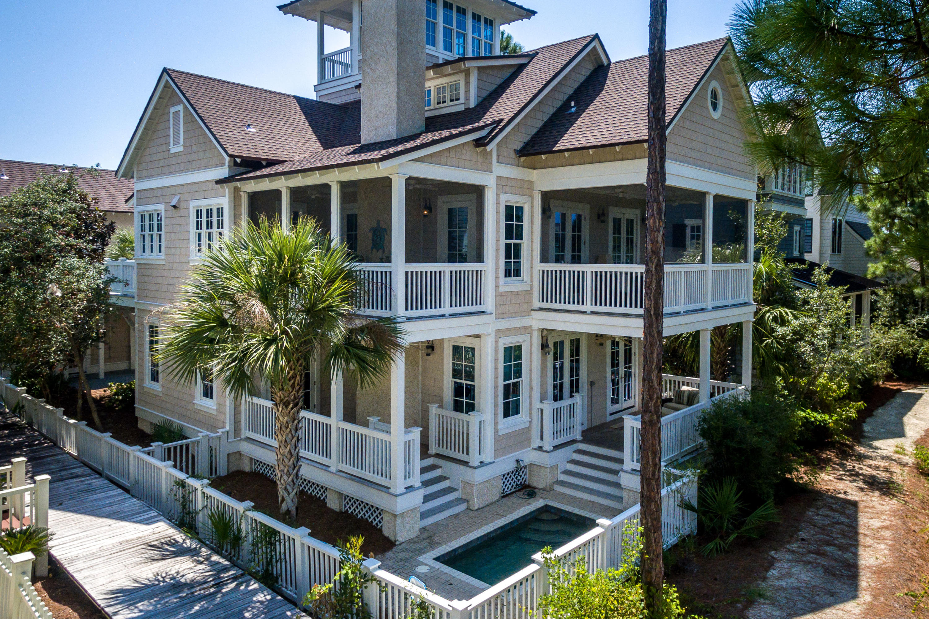 Distinguished by its wood cladding, this classic 3,443 square foot beach retreat combines contemporary architectural influences with historic New England born aesthetic found in the exclusive Gulf front community of WaterSound Beach. This four-story beach house is located just down from one of the winding wooden footpaths that leads to the sugar white sand and emerald waters of the Gulf along WaterSound's private beaches. Boasting warm heart pine wood floors throughout, the main floor living room wrapped in shiplap features double doors that open up to a covered rear porch with comfy outdoor furniture and a heated jacuzzi pool overlooking Yacht Pond. Off of the living room is an oversized bedroom with an ensuite bath that offers access to the covered back porch. The main floor master suit features a walk-in closet and a luxurious ensuite bath with dual vanities and a tile shower. This suite boasts a private covered porch that offers access to the pool with serene lake views. A bunk room, full bath and a main floor laundry room complete this level. The second level of the home was made to entertain while enjoying the views from its spacious open concept layout and two large screened in porches. An oversized living room wrapped in shiplap offers a gas fireplace, a half bath and an additional sitting area. This space opens up to an open dining area and a gourmet kitchen featuring a large island and marble countertops. Complete with a tub sink and Wolf appliances, gas range, double oven,  dishwasher and ice maker, this kitchen is fit for a chef. A spacious sitting room that was made for conversations over coffee offers access to two porches, one screened in and equipped for alfresco dining year-round. Off of this room is a laundry room which features access to a catwalk that transports you out to the carriage house placed over the two-car garage. Featuring a spacious kitchen and a large guest suite with soaring vaulted ceilings, the carriage house offers a sun deck equipped for dining and a porch. The home's third-floor loft space features a sitting area and double doors that open to a spacious living room with vaulted ceilings and a built-in desk area. The spacious well-lit master suite boasts vaulted ceilings, a luxurious ensuite bath with dual vanities, a large tile shower, walk in closet and a private covered balcony. The fourth-floor tower filled with natural light is wrapped in large windows and opens up to a roomy covered balcony featuring gorgeous Gulf views. This coastal WaterSound Beach retreat is a must see tucked away on Shingle Lane.