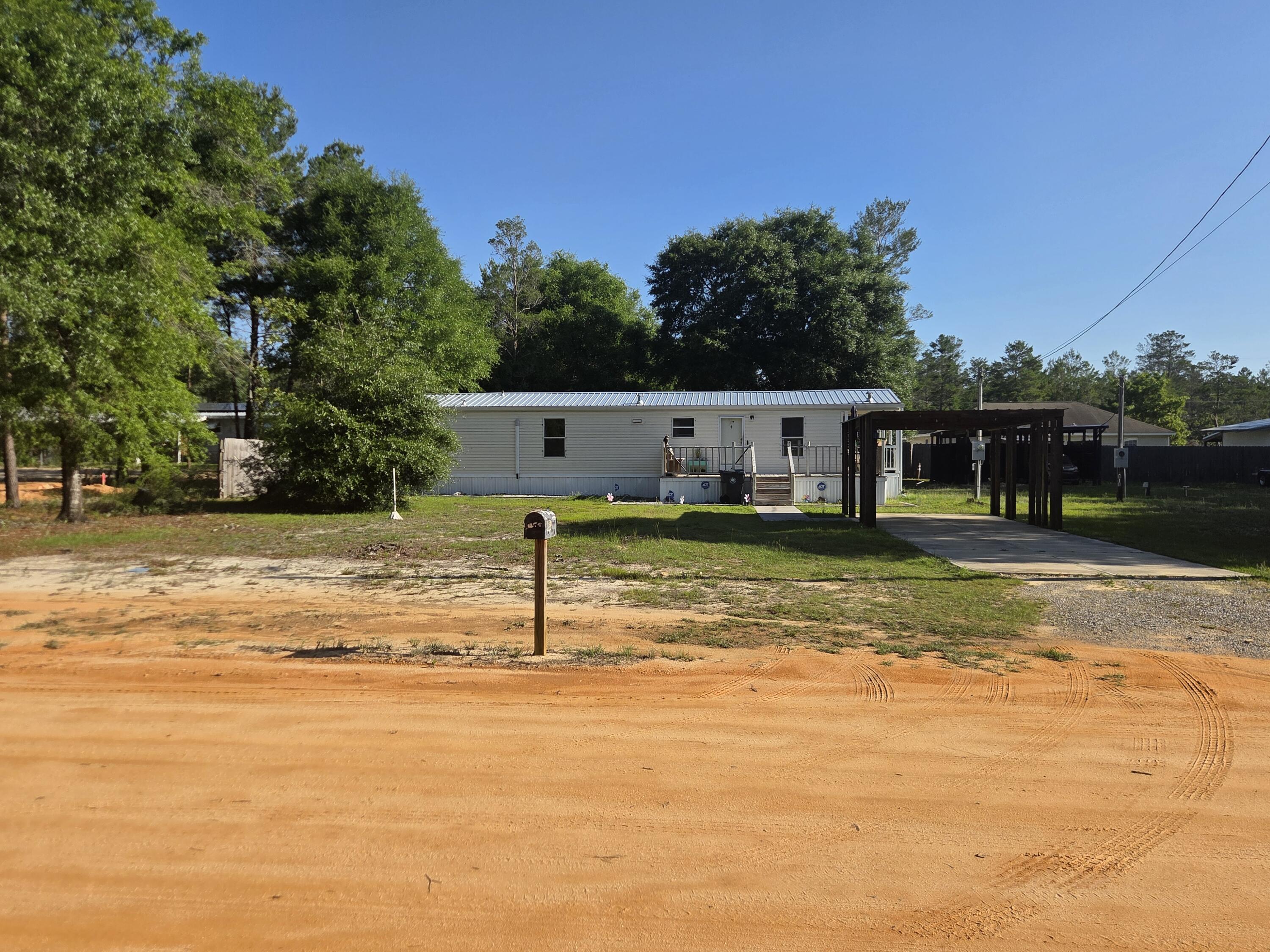 2BR/1BA manufactured home on an oversized 0.46-acre homesite in DeFuniak Springs, comprised of two 0.23-acre lots. Built in 2006 with an efficient 864 SF layout and over $45K in upgrades completed in 2024, including commercial-grade LVP flooring, a mini-split system, deck, galvanized metal roof, gutters, and a new septic system.

Outside features include a carport with additional covered parking, multiple sheds, and a workshop with power, ideal for projects or extra storage. The second 0.23-acre lot includes a septic tank and existing public water and electric hookups already in place, making it perfect for RV parking, future use, or potential resale. Seller will remove the shipping containers at buyer's request. *Information is believed to be accurate. Buyer to verify all information.