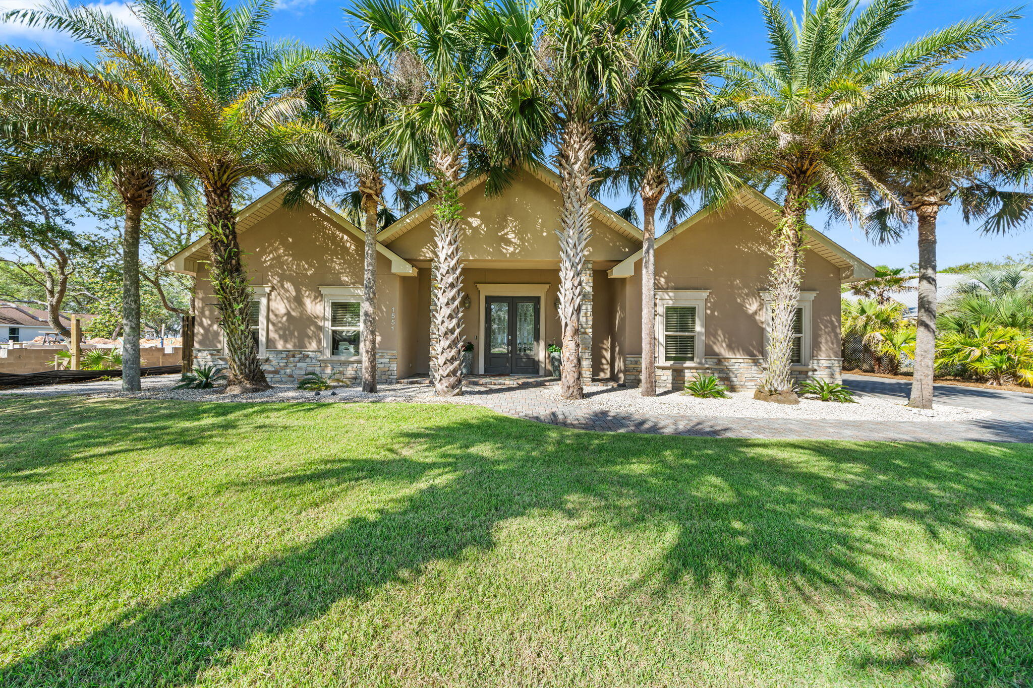 Rare bay-front opportunity in the established Hatchee Shores community of Santa Rosa Beach. Set on nearly half an acre with 100 feet of bay frontage, this beautifully maintained home offers 3 bedrooms, 3 bathrooms, and an open floor plan designed for effortless coastal living. A canopy of mature palms frames the stucco-and-stone exterior, with a brick paver driveway and elegant double glass entry doors flanked by stone columns. Inside, enjoy hardwood and tile floors throughout, crown molding, recessed lighting, and a dramatic stacked-stone fireplace anchoring the great room. The primary suite offers a spa-inspired ensuite with soaking tub, dual vanities, stone countertops, and a walk-in tile shower. Step outside to a covered back porch shaded by grand live oaks, then walk to your private dock where breathtaking open bay views stretch to the horizon - perfect for fishing, boating, or simply watching the sunset. Additional highlights include a large detached workshop/storage building, outdoor shower, carport, and attached garage. Ideal as a primary residence, second home, or income-producing investment. Minutes to the sugar-white beaches of 30A, premier dining, and upscale shopping.