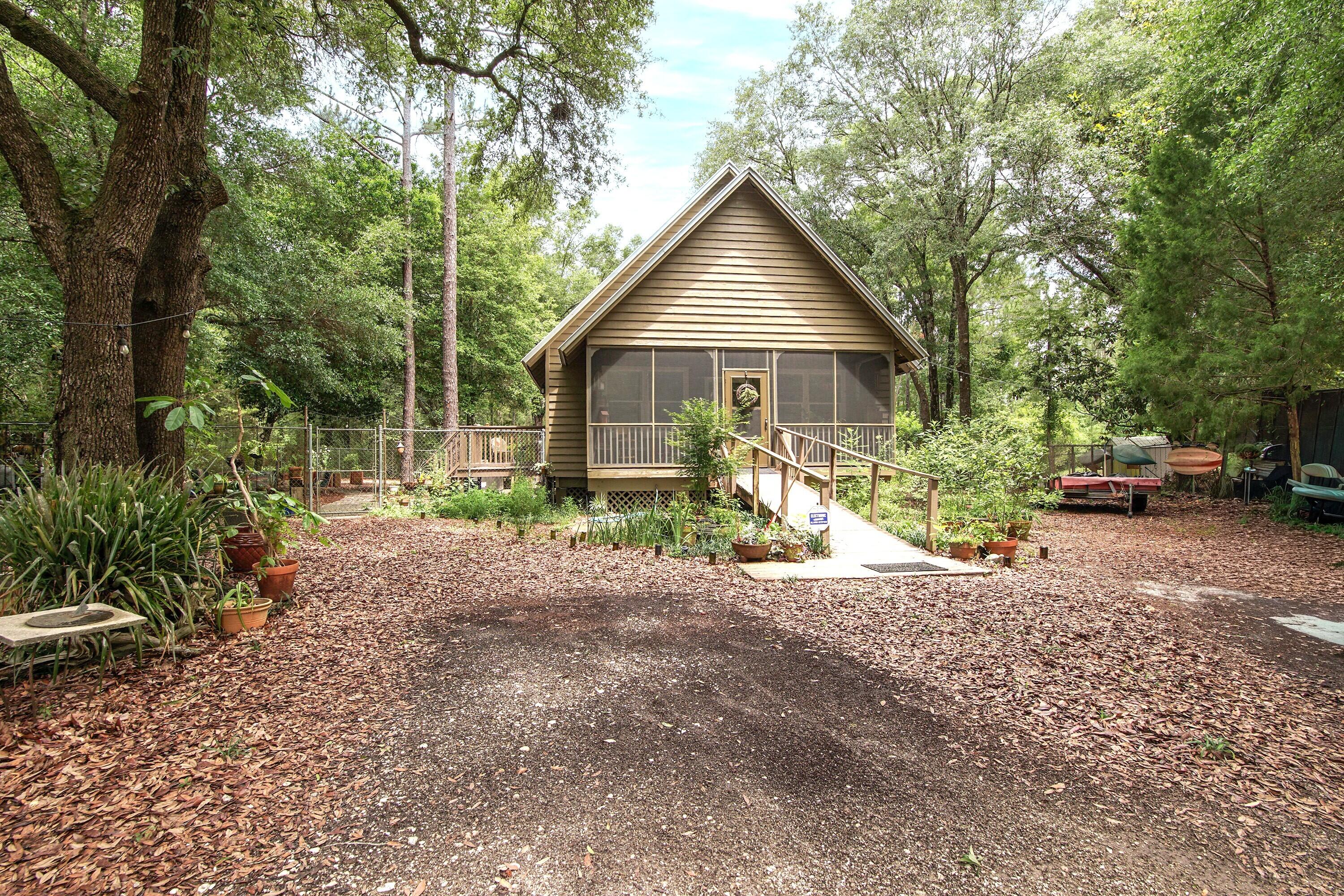 Florida cottage on .79 acres - totally renovated and nestled in a private, serene setting near Black Creek.  This home has undergone a loving renovation replacing dated elements with timeless finishes.  The living room/dining room has eye-catching 8'' ceiling and floor molding, plank walls, original pine wood floors and is open to the second floor above.  The kitchen is totally remodeled with new cabinets, butcher block countertops and stainless-steel appliances.  The downstairs bathroom was totally rebuilt with new everything.  The upstairs bathroom features a new vanity and toilet.  The exterior has beeen repainted, new screens on porch and attic insulation.  Interior improvements include new A/C, plumbing, paint, wood paneling, ceiling fans and laundry closet doors.  The expansive grounds feature multiple private seating areas, a hot tub and a fire pit creating a peaceful, secluded retreat.    A fenced dog kennel and chicken coop are already in place as well as a storage shed. The generous homesite extends beyond the rear fence, offering ample space and flexibility for future expansion, or other enhancements.  A walking trail winds from the home through a scenic wooded setting providing access to the river for kayaking and canoeing and enjoying natural surroundings.  You are within a 20-minute drive to the Gulf.  Feature sheet with all improvements located under document section.  Hot tub, shed and furniture negotiable.  Washer, Dryer and personal items excluded