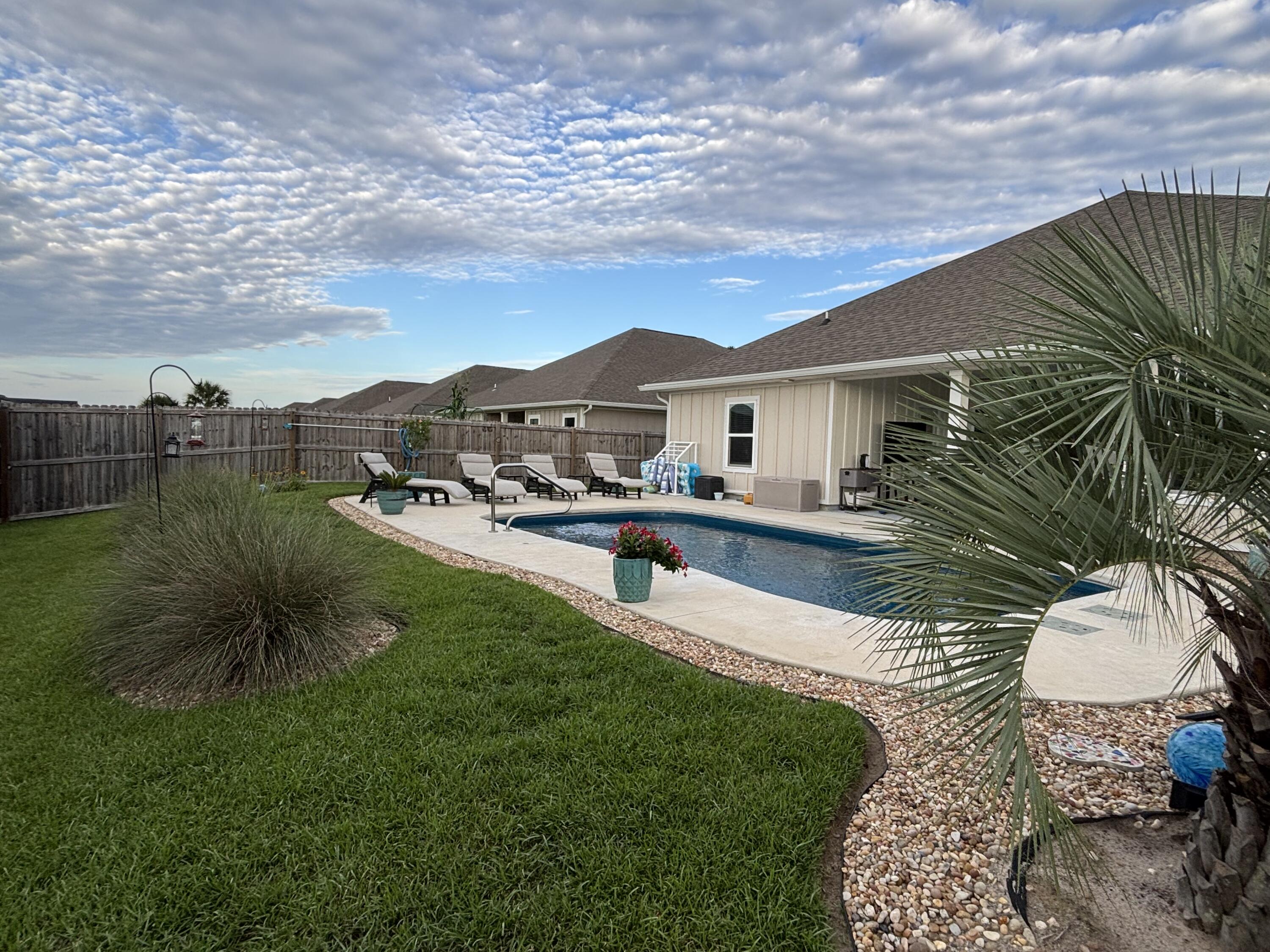 Welcome home to one of the area's most impressive newer construction pool homes, thoughtfully designed with luxury, comfort, and functionality in mind. From the moment you arrive, you'll appreciate the stunning curb appeal, oversized three-car garage, and meticulously maintained landscaping that sets this property apart from the rest.

Inside, you'll find an open and inviting floor plan featuring four spacious bedrooms, three full bathrooms, and a rare bonus office space that many comparable floor plans simply do not offer. Custom carpentry and modern wall accents add character and sophistication throughout the home, while soaring tray ceilings and an abundance of natural light create a bright and airy atmosphere.

The heart of the home is the expansive kitchen, complete with a massive center island, generous cabinetry, and all appliances conveying with the sale--perfect for entertaining family and friends. The private owner's retreat is tucked away overlooking the pool and offers a true spa-like experience with a separate soaking tub, walk-in shower, and oversized walk-in closet.

Step outside and prepare to fall in love. The backyard is truly a showpiece, featuring a custom-designed pool with elegant hardscaping, beautiful fountains, and resort-style finishes. Every detail has been carefully planned and maintained--from the lush lawn and mature palms to the decorative rock landscaping--creating a backyard oasis you'll enjoy year-round. The third full bathroom conveniently offers direct access to the pool area, making outdoor living effortless.

Located in a desirable community with sidewalks, underground utilities, low quarterly HOA dues, and an easy commute to Pensacola, Fort Walton Beach, and Destin, this home offers both luxury and convenience. Enjoy breathtaking sunrises, stunning sunsets, and the peace of mind that comes with being outside of a flood zone while benefiting from low insurance costs.

Rarely do pool homes of this caliber become available at such an attractive price point. Professional photography will be available soon. Sellers are seeking a late July or early August closing date. Pre-approved buyers only, please.

This is more than just a home--it's a lifestyle. Schedule your private showing today and discover why you'll fall in love the moment you arrive