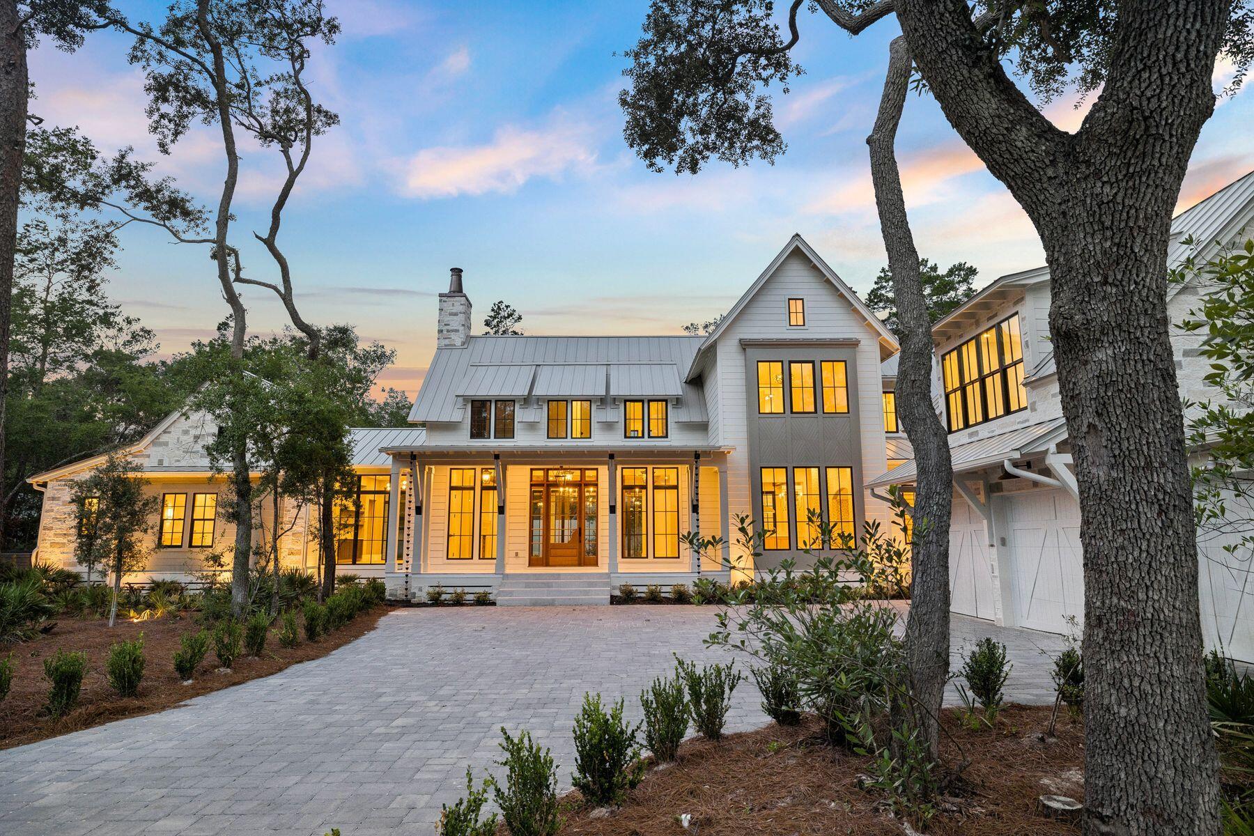Nestled on a half-acre lot among centuries-old oak and pine trees in the historic community of Point Washington, this newly constructed residence sets a new standard for what luxury coastal living can look like. The builder is a known curator of fine homes, and the level of craft on display here reflects a career spent sourcing materials from the world's great workshops -- France, Spain, Morocco, Belgium, Turkey, and England -- and assembling them with uncommon intention. At 5,390 square feet across two floors, with six bedrooms, five and a half bathrooms, and a dedicated spa, the home is designed so that all principal living can be done on a single floor. More than 1,374 square feet of outdoor living space connects the interior to a backyard designed for both quiet mornings and effortless entertaining. The exterior is clad in Peppered Limestone quarried in Texas and lit by handmade Bevolo gas and electric lanterns. Inside, the foyer is floored in Venetian Grey and White Tumbled Marble imported from France, with E.F. Chapman lanterns overhead. Eight-inch French hardwood floors run throughout, beneath reclaimed and imported French Oak beams finished with natural oil. Walls are finished in custom plaster, with limewashed surfaces in the office and primary bedroom lending a warmth that paint simply cannot replicate.
Outside, the rear of the home is designed for serious outdoor living. A resort-style pool and hot tub are set within Flemish Grey Limestone decking, and a covered living area features a fireplace, wood ceiling, and Bevolo lanterns. The fully equipped outdoor kitchen includes a six-burner Coyote grill, refrigerator, and leathered countertop. An outdoor shower, astroturf lawn accessible from the primary bedroom, and a scalloped privacy wall complete the picture. The bay is just moments away, and the surrounding oak and pine canopy provides a natural privacy that no fence could replicate.
The main living area occupies the entire first floor, with the kitchen, living, and dining rooms flowing together in an open, unhurried plan. The living room is anchored by beautiful reclaimed beams overhead, and a Nana door opens fully to the backyard, connecting the interior effortlessly to the outdoor entertaining space beyond. The kitchen is anchored by a full Thermador appliance suite, a Shaw's sink imported from England, and a Sub-Zero wine refrigerator. Custom oak cabinetry with brass hardware runs throughout, and the island -- topped in quartz and hung with Suzanne Kasler concrete pendants -- is sized generously for seating and gathering. Behind a discreet door, a fully equipped scullery with a plumbed Miele coffee maker keeps the main kitchen clear and composed.
The primary bedroom is a considered retreat -- limewashed plaster walls, a hand-painted pecky cypress herringbone feature wall, a center beam of reclaimed imported French Pine, and Spanish Alabaster stone sconces. A fireplace anchors one wall, and direct access to the porch and pool area is just steps away. The primary bathroom offers heated marble floors, his and hers vanities, Brizo fixtures throughout, and a large shower with gold fixtures and an oversized rain head. The primary closet is generously sized with enclosed shelving and a built-in makeup vanity.
A first floor guest bedroom with en-suite bath finished in imported Zellige Moroccan tile offers its own private exterior access. A dedicated office with limewashed walls provides a calm and considered workspace. Practical spaces -- a mudroom, laundry room with dog bath, and powder room with an imported Turkish sink -- are finished with the same care given to the principal rooms.
Built-in speakers, designer lighting, and brass hardware throughout speak to a home where the details were never an afterthought.
Upstairs, the home offers a large bedroom with reclaimed wood beams, a charming blue bedroom, a flex room suited to a study or children's space, and generous sitting areas. Two well-appointed bathrooms serve the level, one of which is a showpiece of blue and white penny tile with a matching vanity and shower. A large closet with dedicated shoe storage and a sweeping covered outdoor porch complete the upper floor.
The wellness suite is in a category of its own. Belgian Bluestone floors, a custom cold plunge tub, a two-person infrared red light sauna with Bluetooth, and a Moroccan plaster steam shower with island stone floors together create a space devoted entirely to restoration. Few homes at any price point offer this combination under one roof.
Above the oversized three-car garage, a self-contained carriage house with oak floors, oak wall paneling, a full kitchen, and a penny tile bath offers complete independence for extended family or long-term guests -- a fitting complement to a home of this caliber.