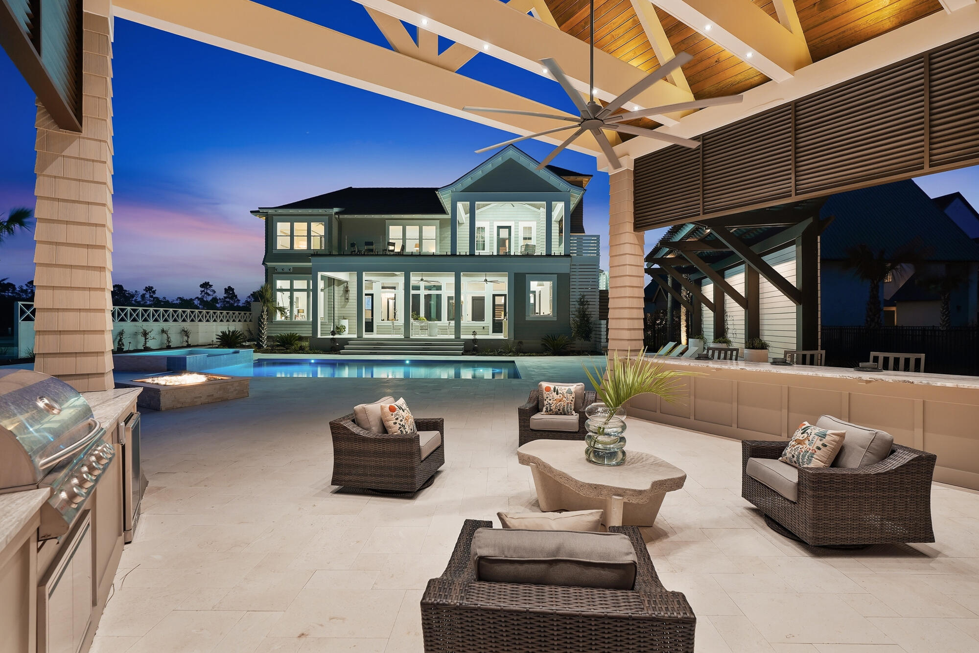460 Golfridge Drive presents an architecturally striking coastal estate in Inlet Beach, offering approximately 8,700 square feet of total combined area. This impeccable resort style residence includes 5,714 square feet of living area, 1,000 square feet of heated and cooled garage space, and an additional 1,986 square feet encompassing a pool cabana with full bath, covered porches and viewing terraces. Defined by refined craftsmanship, curated materials, and thoughtfully designed indoor and outdoor living, this exceptional property is set within the prestigious gated community of WaterSound Camp Creek. Inside, the home's scale and natural light create an immediate sense of openness. Twelve-foot ceilings run throughout, while select spaces rise to vaulted heights of 15 to 18 feet, enhancing the airy, gallery like atmosphere. Seven inch engineered white oak flooring flows throughout the residence, complemented by custom white oak cabinetry and carefully curated designer lighting. Six of the home's seven bedrooms are positioned to capture tranquil water views, creating a serene backdrop that extends the home's connection to its surrounding landscape.

At the heart of the home, an extraordinary Italian made all glass Chanel design chandelier cascades through the main living space like a piece of modern sculpture. Designed to capture and refract light from every angle, the chandelier becomes a breathtaking architectural focal point that anchors the room with unmistakable elegance and establishes the tone for the home's elevated interiors where architecture and artistry meet.

The primary kitchen pairs elegant design with exceptional functionality. Custom white oak cabinetry, dual 48 inch professional gas ranges, and a dedicated wine chiller and serving station anchor the space, while a nearby wine room with built in racks set against an oak feature wall offers a striking setting for displaying and enjoying a curated collection. Designed with collectors in mind, the wine room features custom oak storage for 154 individual bottles along with 18 case style compartments that provide additional space for expanding a thoughtfully curated collection. The adjoining living area centers around a gas fireplace, creating warmth and balance within the expansive gathering space.

Bathrooms throughout the home reflect the same attention to detail, featuring fully tiled showers, custom crafted vanities, and refined designer fixtures, while curated furnishings and finishes by John Richard introduce a tailored, design forward aesthetic.

Outdoor living unfolds across beautifully composed spaces designed for both relaxation and entertaining. A spacious sun terrace overlooks the heated pool and spa, custom pavilion, and tranquil lake views, framed by tempered impact glass railings that preserve unobstructed sightlines across the landscape.

Below, the backyard becomes a private retreat. White limestone pavers surround the pool deck, while a custom built gas fire pit creates a welcoming focal point for evenings outdoors. A striking vine covered pergola wall and extensive landscape lighting add depth and architectural texture to the outdoor setting.

The pool house pavilion extends the home's entertaining capabilities with a fully equipped outdoor living area featuring a 70 inch television, electric fireplace, Blaze stainless gas grill, bar refrigerator, and outdoor sink, along with a full bathroom and storage. A whole home Bose sound system provides seamless audio throughout the interior and outdoor living spaces, enhancing gatherings large or small.

Additional architectural details include Decra stone coated aluminum shake roofing, natural gas copper lanterns, insulated windows, a laundry chute from the second floor, central vacuum system, and a heated and cooled three car garage designed for both convenience and flexibility.

With its generous scale, exceptional craftsmanship, and beautifully integrated indoor and outdoor living spaces, 460 Golfridge Drive offers a sophisticated interpretation of coastal living where architectural integrity, designer finishes, and resort style amenities come together in one of 30A's most sought after private club communities.