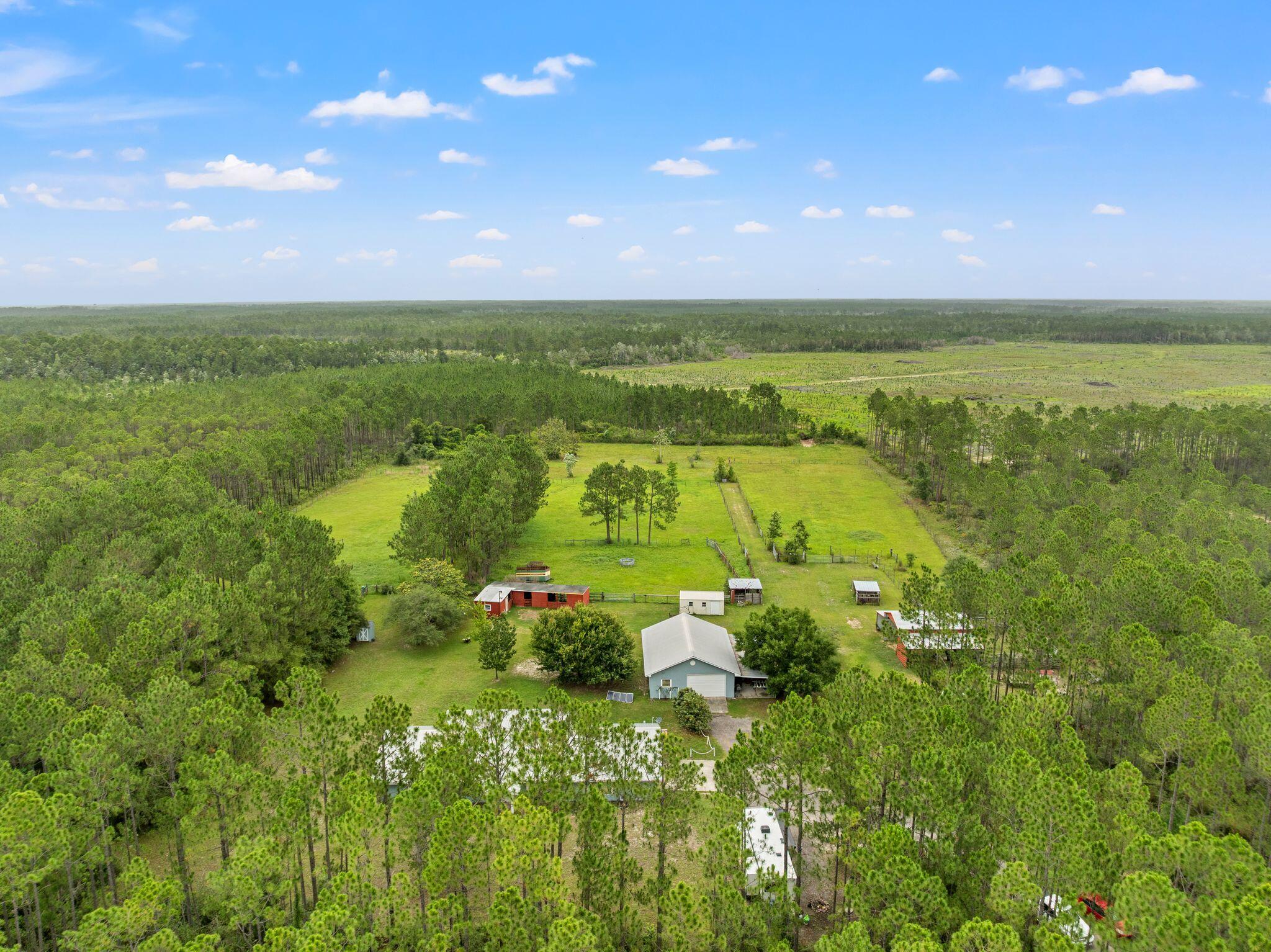 9140 Steel Field Road: Where 11+ acres of privacy meet the convenience of coastal living. Located less than 10 miles from the sugar-white sands of Panama City Beach and just a short drive to Scenic 30A, Margaritaville, and ECP International Airport, this unique property offers the best of both worlds. The 3-bedroom, 2-bath home features over 2,100 square feet of heated and cooled living space with a functional split floor plan, spacious kitchen, great room, family room, garage, and additional climate-controlled storage room. Tile and plank flooring run throughout the home, complemented by a metal roof, covered back porch, and full-size laundry room with utility sink. Ideal for farming, livestock, or equestrian use, the property includes two barns, stables, fenced pastures, corrals, a partially cooled workshop/butcher shop, storage shed, detached solar-powered garage, and an underground storm shelter. With Conservation Habitation zoning, potential to be subdivided into two parcels, and future land use designated as Village Center allowing certain commercial uses, this property offers exceptional flexibility for homeowners, farmers, and investors alike. Rarely does a property combine acreage, privacy, development potential, and proximity to the beach like 9140 Steel Field Road. All measurements are approximate; Buyer to verify.