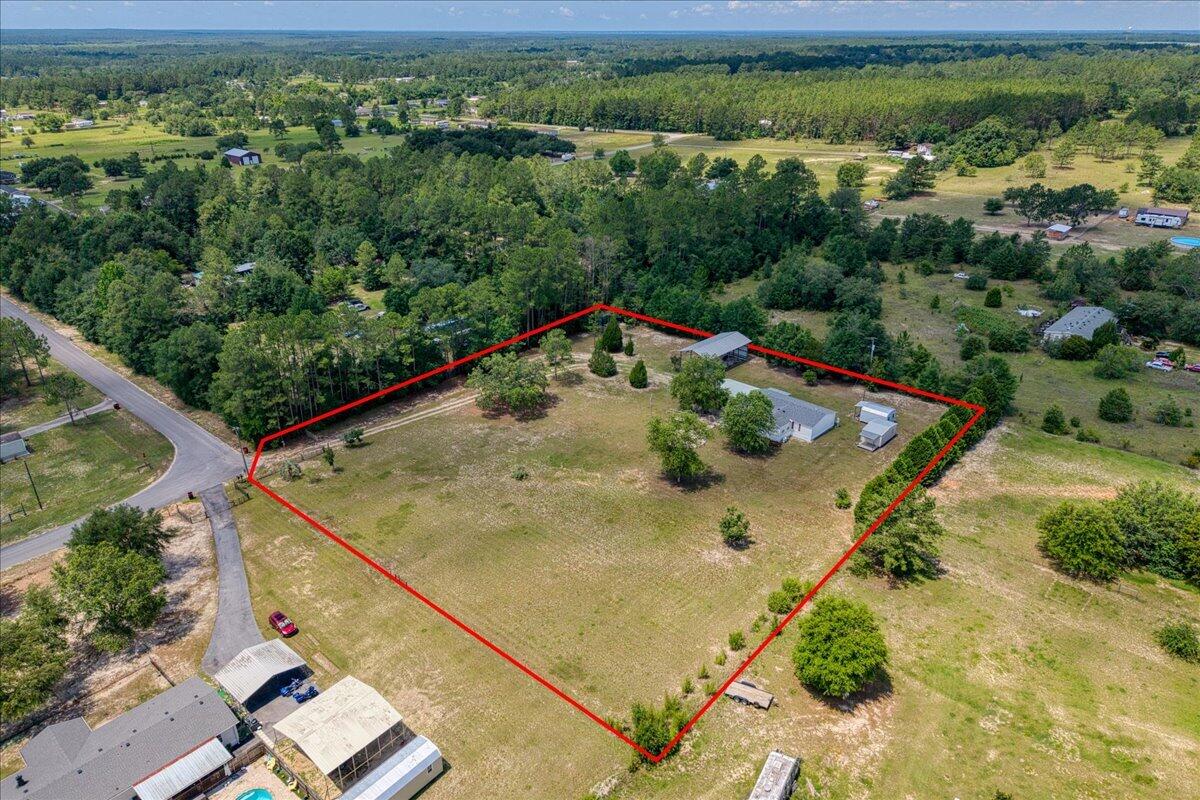 Come experience country living in Milton! Situated on 2.4 FULLY fenced acres and featuring a 2023 roof, this meticulously maintained three-bedroom, two-bath home offers the ideal homestead setup with plenty of room for your hobbies, equipment, boats, RVs, and more - with NO HOA. Surrounded by mature trees and located on a desirable corner lot, the property provides a secluded feel while remaining conveniently close to modern amenities. Inside, you'll find a spacious and functional floor plan featuring a large kitchen with an island, breakfast nook, dedicated dining room, and a bright living room filled with natural light. The living room offers direct access to the yard and firepit area, creating a space for relaxing or entertaining. The split-bedroom layout provides privacy, with the primary suite featuring an en suite bathroom complete with double vanities and a walk-in shower. Two additional bedrooms are located on the opposite side of the home and share a full bathroom with a tub/shower combination. The property is packed with valuable improvements and versatile outbuildings. A climate-controlled 12x20 shed currently serves as a gym and features electricity, insulation, finished walls, and flooring. Additional structures include a 12x16 storage shed with electricity and lighting, a 24x48 pole barn with power and an RV hookup, an 8x20 shipping container, and a two-car carport with a concrete pad. A sprinkler system has been added to help maintain the grounds. Conveniently located just off Highway 87 with easy access to Interstate 10, this property is only 25 minutes from Navarre Beach. Whether you're looking for a private retreat, farm potential, or the perfect place to spread out and enjoy country living, this exceptional Milton property is ready to welcome you home!