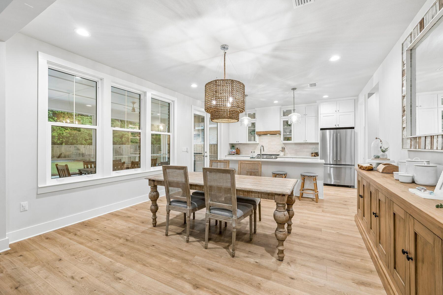 Tucked within the gated bayfront community of Steamboat Landing at Hammock Bay, this thoughtfully designed, CUSTOM, single-level residence offers an exceptional combination of privacy, functionality, and indoor-outdoor living. Positioned on a large homesite backing to a serene wooded buffer, the property enjoys a peaceful setting with a spacious fenced backyard designed for both entertaining and everyday enjoyment. Beautiful landscaping and a welcoming approach set the tone upon arrival, while the attached two-car garage and well-planned layout provide effortless convenience. The expansive backyard is a standout feature, complete with a large paver patio and grilling area, dedicated fire pit space, and an oversized screened porch with ample room for both dining and lounging, all overlooking the private natural backdrop. Inside, the home's flowing floor plan was designed with both comfort and connection in mind. A welcoming foyer opens into the spacious living room, anchored by a built-in brick fireplace, before seamlessly transitioning into the dining area and stunning kitchen beyond. The kitchen serves as the heart of the home with a large center island, gas range, range hood with natural wood accents, neutral tile backsplash, and an oversized walk-in pantry. Large windows throughout the living, dining, and kitchen spaces create a bright and inviting atmosphere while offering uninterrupted views of the backyard and wooded surroundings. Positioned at the rear of the home for maximum privacy, the primary suite overlooks the backyard and wooded buffer and features dual vanities, a walk-in shower, and a spacious walk-in closet. Two additional guest bedrooms each include walk-in closets and share a Jack-and-Jill style bathroom, while a separate powder bath adds convenience for visitors. Privately situated off the kitchen, a mudroom hallway and laundry area connect to a secluded fourth bedroom featuring its own ensuite bath and generous walk-in closet, ideal for guests or multigenerational living. Residents of Steamboat Landing at Hammock Bay enjoy an amenity-rich lifestyle with access to the expansive community offerings. Steamboat Landing provides a more intimate bayfront setting complete with a waterfront clubhouse, dock, and picturesque walking trails shaded by mature oak trees. Hammock Bay further enhances the lifestyle experience with multiple pools including two zero-entry resort-style pools, a traditional lap and recreation pool, a state-of-the-art 10,000-square-foot fitness center, more than 12 miles of trails and bike paths, playgrounds, lighted pickleball and tennis courts, and a basketball court, the popular Props Brewery, and a community amphitheater.