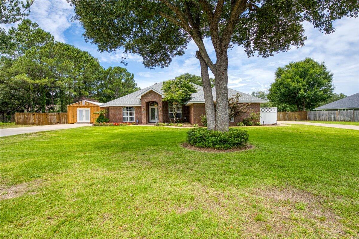 Welcome to your private slice of paradise in Navarre! Situated on a beautifully maintained 1-acre lot just 10 minutes from Navarre Beach, this stunning 4-bedroom, 2.5-bath brick POOL home offers space and freedom with NO HOA! This property boasts exceptional curb appeal featuring mature landscaping, a side-entry 2-car garage, and TWO driveways providing ample parking for vehicles, boats, RVs, or trailers. Step inside to discover elegant architectural details including 10-foot ceilings, arched doorways, tray ceilings, and a formal dining room highlighted by a double-sided gas fireplace. The open-concept living area features arched built-ins and an impressive 8-foot cascading sliding glass door that seamlessly connects indoor and outdoor living. The spacious kitchen has solid wood maple cabinetry, granite countertops, stainless steel appliances, a gas range, an island, breakfast bar, and adjoining breakfast nook. Outside, your screened lanai and backyard oasis await! Enjoy the sparkling in-ground pool complete with a waterfall spa feature, surrounded by a fully fenced backyard with mature shade trees and endless room for recreation. The yard houses TWO storage sheds, a climate-controlled workshop accessible from both the front and backyard equipped with a rear concrete slab and double-gate access on both sides of the property. Retreat to the oversized primary suite, thoughtfully split for added privacy. The luxurious primary bath features dual vanities, two walk-in closets, a g arden tub, separate shower, and private water closet. Two guest bedrooms share a convenient Jack-and-Jill style bathroom, while a fourth bedroom is located near the front of the home. A half bath off the main living area is perfect for guests. Conveniently located just minutes from Navarre Beach, shopping, dining, and top local amenities, this exceptional property offers the quintessential Florida lifestyle with room to live, work, play, and store all your toys!