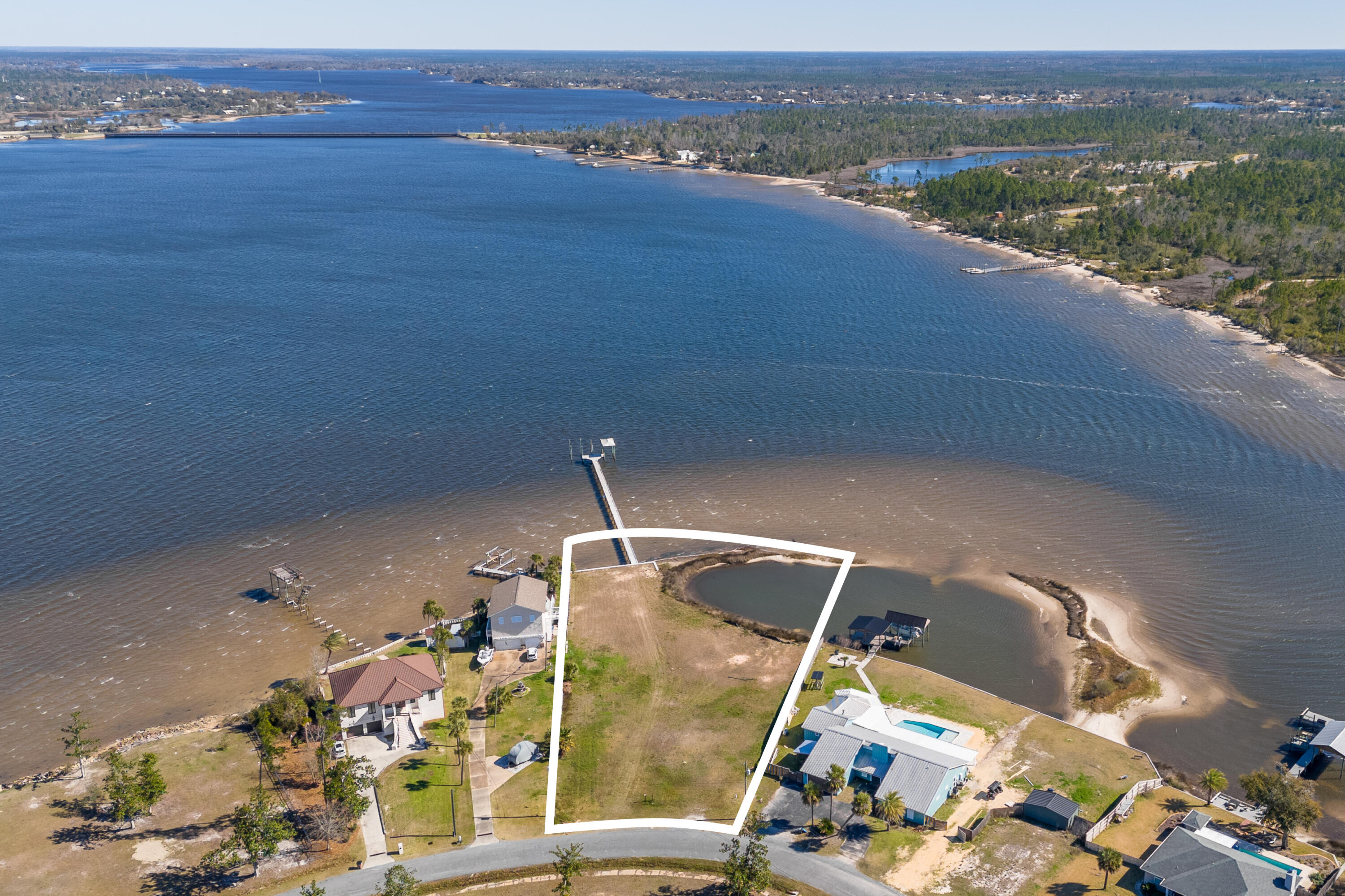 A rare stretch of North Bay shoreline sets the stage for something extraordinary. Two separate lots, spanning 1.2 acres with an impressive 222 feet of deepwater frontage, this offering presents a remarkable canvas for a custom waterfront estate defined by space, privacy and possibility. A solid seawall is already in place, along with a large private dock and boat slips, allowing you to step straight into the bayfront lifestyle from day one. Launch at sunrise, cruise at sunset or simply let the rhythm of the water shape your days. With deepwater access, boating enthusiasts will appreciate the freedom and flexibility this setting affords. What truly distinguishes this property is its own small island feature, creating a natural buffer and a protected cove feel just off your shoreline. The result is a uniquely intimate waterfront experience, where calm waters and wide open bay views exist in perfect balance. It is a setting that feels both expansive and tucked away, offering room to design a legacy home with sweeping outdoor living spaces, a resort-style pool or lush coastal landscaping framed by panoramic water vistas. Located in College Point and near Isaac Bird Park, this homesite pairs serene bayfront living with convenient access to green space and recreation. Properties with this much frontage, acreage and character are increasingly scarce. Here, the foundation for your vision is already in place; all that remains is to bring it to life.