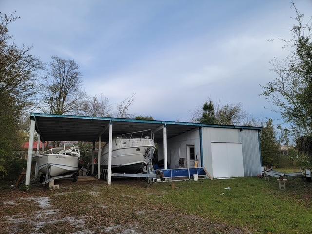 Property is over a half  acre.  It is near the bay and across the street from homes on the canal.
It has a 3 bays parking for cars, boats or your toys.  It has an attached concrete floor workshop with shelves etc. Size is 22x31 for attached covered parking and shop is 16x22.  It has had electric to the shop.  Lot is some cleared and ready to build your dream home.  I think if you built a
two story house you probably could have a view of the bay.  Buyer to verify all information including schools.