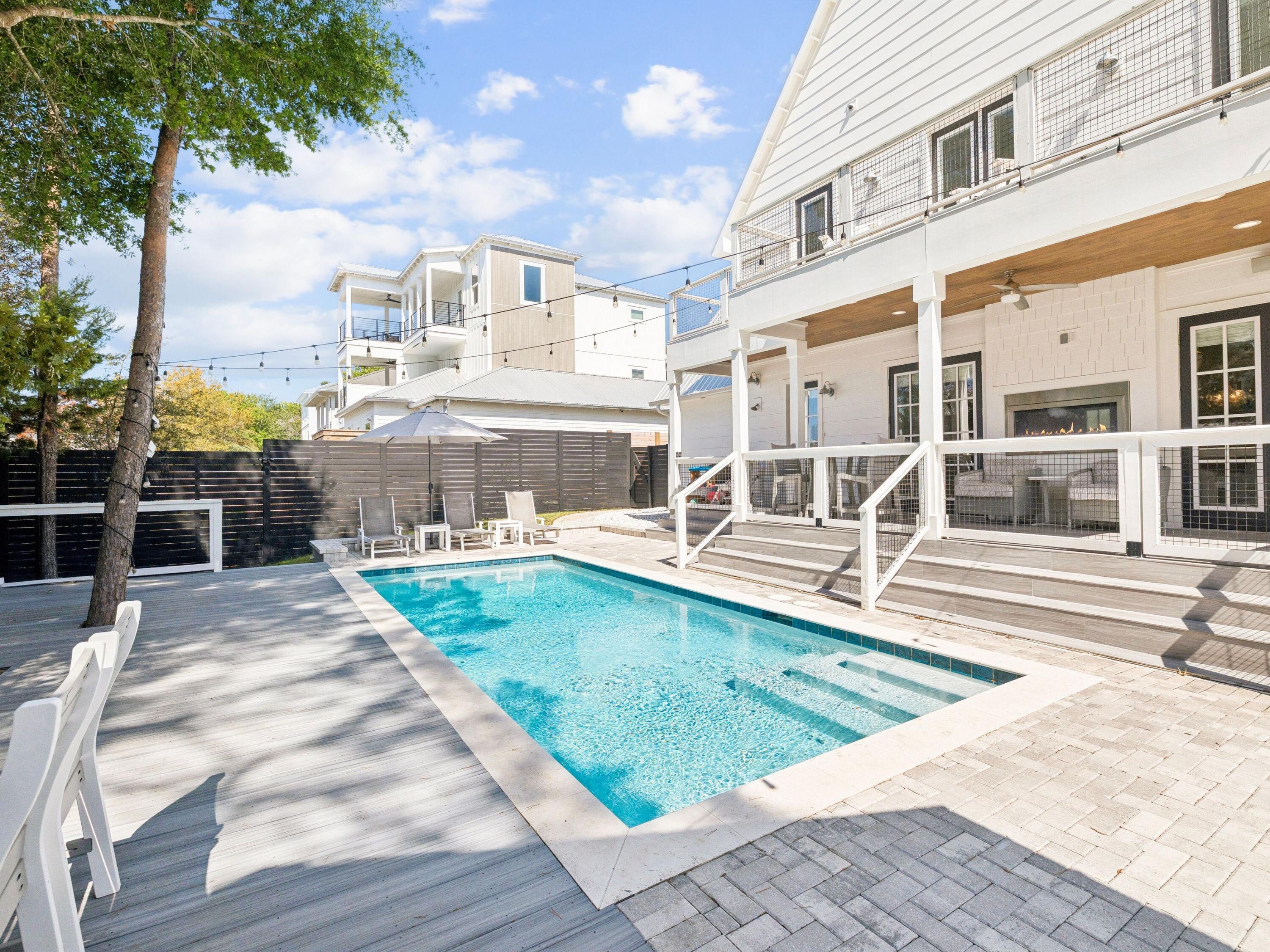 Located in the highly sought-after Gulfview Heights community on the west end of 30A, 214 Woodland Drive offers an exceptional blend of architecturally refined coastal design, prime location, and proven income potential just moments from the beach, dining, and boutique shopping. Designed to impress as both a full-time residence and high-performing rental, this 4 bedroom, 3.5 bath home is already generating strong rental income in its first year while still presenting like new. Offered fully furnished and turnkey ready, including a golf cart for easy cruising along 30A, this property is ready for immediate enjoyment or continued rental success. The private backyard is a true showpiece, featuring a resort-style pool, expansive deck, ambient string lighting, and a beautifully appointed summer kitchen, creating an elevated outdoor living experience ideal for entertaining or relaxing in style.

Inside, the home showcases a thoughtfully curated design with high-end finishes and a layout that effortlessly balances sophistication and functionality. The open concept living area is light-filled and inviting, anchored by a striking double-sided contemporary fireplace that not only adds architectural interest but provides substantial warmth. The chef's kitchen is equally impressive, featuring a waterfall-edge island, butler's pantry, premium appliances, and designer finishes that flow seamlessly into the dining and living spaces.

The main level primary suite offers privacy and convenience, while an additional first floor bedroom or office provides flexibility for today's lifestyle. Upstairs, the home continues to impress with a spacious secondary living area featuring vaulted ceilings accented with exposed beams, creating a warm yet elevated retreat. Two of the secondary bedrooms also showcase these architectural beam details, adding character and visual interest throughout the upper level. A generous landing area with built-in shelving, an adorable reading bench as well as a functional desk, offers the perfect setting for remote work or study, while the custom three-level bunk nook adds a distinctive and memorable feature ideal for guests and sleepovers. Additional bedrooms and living spaces open to a private balcony, offering a peaceful escape among the treetops.

Beloved by locals for its welcoming, family-friendly atmosphere, Gulfview Heights remains one of the most desirable communities along 30A. Whether you are seeking a primary residence, second home, or a luxury investment property, this home delivers a rare combination of elevated design, exceptional outdoor living, and effortless coastal lifestyle.