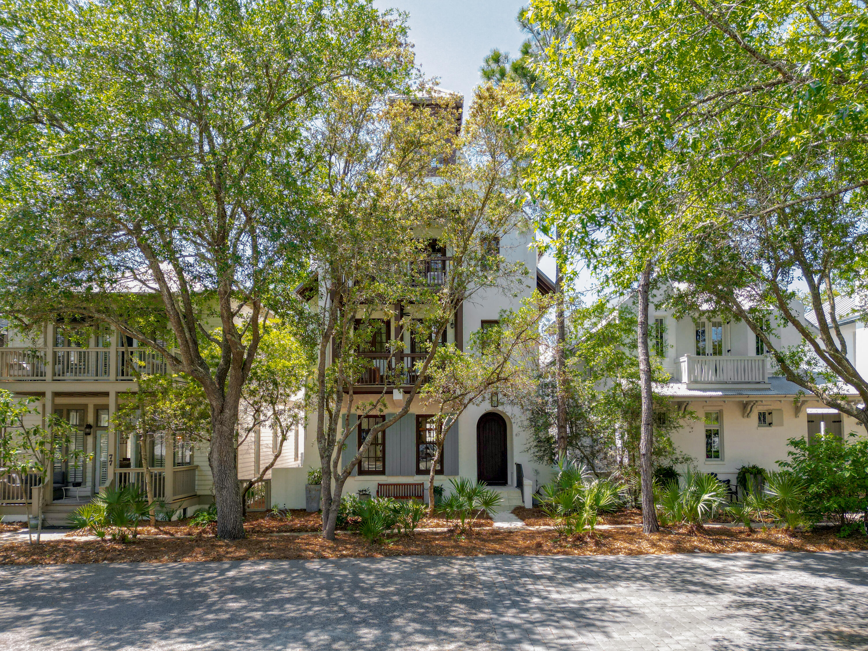 Designed by award-winning architect Tim McNamara, 87 Bridgetown Avenue is a rare large-format family retreat ideally positioned on one of the quietest and most desirable streets in Rosemary Beach. Thoughtfully designed for multigenerational living and effortless entertaining, this exceptional courtyard residence combines architectural character with the practical functionality rarely found in Rosemary Beach.  Spanning approximately 4,380 square feet, the property offers expansive gathering spaces, multiple indoor and outdoor living areas, elevator access to all levels, and exceptional sleeping accommodations for large families and guests. The main residence features three spacious king suites with private en suite baths, each complemented by its own private balcony, creating peaceful retreats throughout the home. A second-floor bunk area provides additional accommodations ideal for children or overflow guests, while the inviting living and dining spaces are designed for comfortable long-term stays rather than simply weekend occupancy. The first-floor living area is further enhanced by a warm and inviting wood-burning fireplace.  Encompassing the entire third floor, the luxurious approximately 1,251-square-foot primary suite serves as a true private retreat, offering exceptional scale, privacy, and comfort rarely found in Rosemary Beach. The suite provides an elevated owner experience while maintaining separation from the home's guest and family gathering areas, and includes a spacious spa-inspired bath featuring a relaxing Jacuzzi soaking tub. Additional features of the primary suite include a private wet bar with mini refrigerator and a gas log fireplace, creating a peaceful and luxurious owner sanctuary.  At the center of the home, the beautifully designed first-floor courtyard offers a private spa pool and inviting outdoor living space, creating an ideal setting for entertaining, relaxing after the beach, or enjoying quiet evenings with family and guests. The courtyard is anchored by an outdoor fireplace and a fully appointed outdoor kitchen featuring a Viking gas grill, sink, and mini refrigerator.  Above the detached two-car garage, the carriage house creates a true private guest retreat with an additional king bedroom, bunk room, full bath, half bath, kitchenette, and its own private balcony--perfect for extended family, grandchildren, visiting guests, or private owner accommodations.  One of the home's most valuable and increasingly rare features is its exceptional parking capacity. The property comfortably accommodates four private on-property parking spaces, including a two-car garage and two additional off-street spaces behind the garage, while also benefiting from unusually favorable street parking along quiet Bridgetown Avenue.  Ideally situated near several of Rosemary Beach's most desirable owner amenities, the home enjoys close proximity to the Cabana Pool, the Owner's Pool, and the exclusive Owner's Pavilion--offering exceptional convenience for families, children, and guests while maintaining a peaceful and less congested setting within the community.  The location also provides easy access to the Town Center, St. Augustine Green, shopping, dining, and the beach, creating an ideal balance of privacy, walkability, and resort-style living.  Rich architectural details including Brazilian walnut hardwood flooring, pecky cypress millwork, multiple porches, and beautifully integrated outdoor spaces further distinguish this exceptional property. Rarely does a Rosemary Beach home combine this level of scale, functionality, parking, flexibility, and family-oriented design in such a premier location.