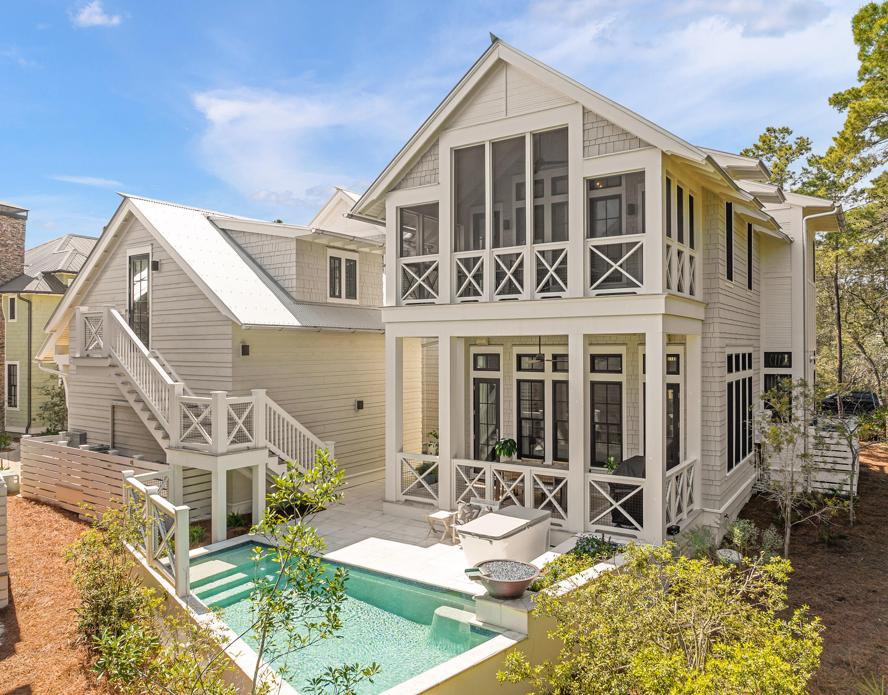 If you've been looking for the right home in Draper Lake Coastal Village, this home offers a compelling opportunity within the gated enclave. Designed by acclaimed architect Geoff Chick and built by Chris Clark, this 3,521-sq.-ft. residence offers four bedrooms, four-and-a-half baths, and the kind of approachable scale and thoughtful design that works equally well as a full-time coastal home or a second home you never want to leave. Walk through the front door, and a two-story foyer with floor-to-ceiling glass fills the entry with natural light. Hardwood floors lead into an open living area where 12-foot coffered ceilings with pecky cypress insets frame the space. The combined volume of the kitchen, dining, and living areas leaves a lasting impression. A marble-topped island anchors the kitchen with a professional-grade appliance package, while a fireplace brings balance to the living area. A first-floor guest suite, along with a powder bath, laundry, and two-car garage, completes the main level. Upstairs, vaulted ceilings define the primary suite, which features a soaking tub, walk-in shower, double vanity, and generous closets. A second guest suite, additional living area, and screened porch provide flexible space to unwind or work. Thoughtfully placed laundry on both the main and second floors for effortless day to day living. A detached carriage house with private exterior access offers a self-contained space with a kitchenette and ensuite bath, ideal for a guest suite, workout room or office space. Outside, a private heated pool and covered porches create an easy indoor-outdoor connection. Draper Lake Coastal Village is a gated community on Scenic Highway 30A inspired by the great camps of the Adirondacks and Lake Champlain. Designed by the planners behind Seaside, Florida, Rosemary Beach, and Alys Beach, the neighborhood is set along a rare coastal dune lake and offers pools, boathouses, trails, and a private beach cabana, all just moments from dining, shopping, and the 30A bike path.