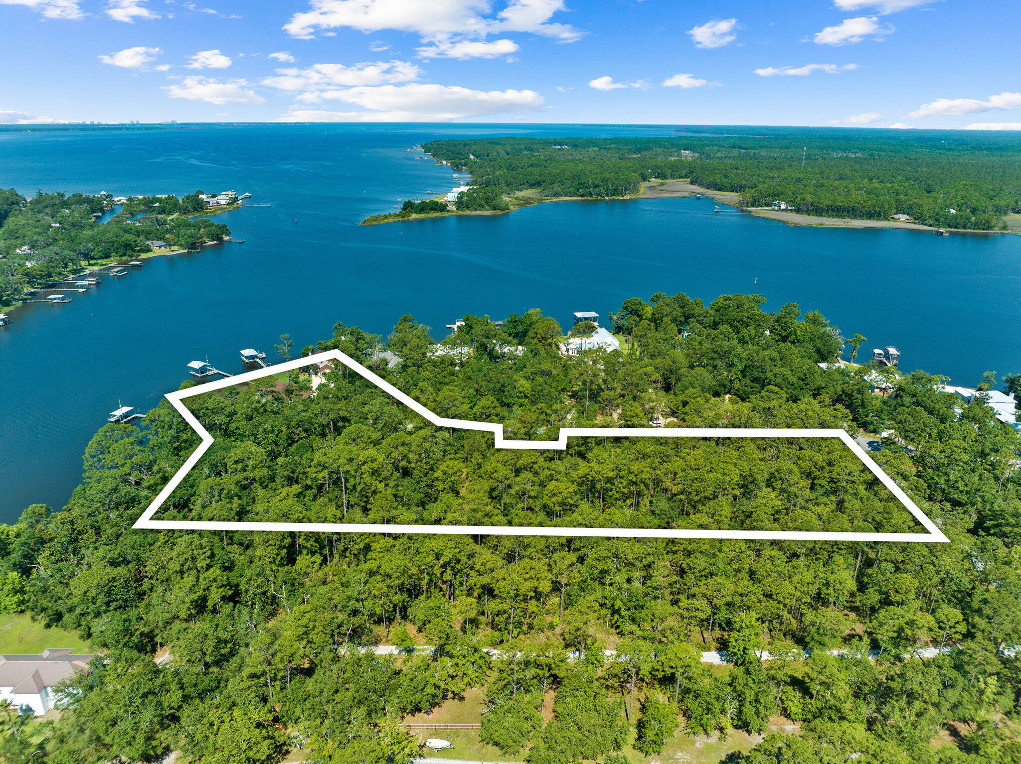 Set on a rare 6.8-acre point along Lagrange Bayou, this offering is unlike anything else on the market in Freeport -- an unmatched combination of 725 feet of waterfront, two single-family homes, a versatile third structure, and three private docks, all positioned to capture the best sunset views on the water.
Perched on the point, this property is oriented to soak in panoramic water views across the bayou and into Choctawhatchee Bay, with front-row seats to some of the most spectacular sunsets in the area. Wildlife is part of everyday life here -- herons wading the shallows, dolphins gliding past the docks, and eagles, osprey, and deer moving through the property's wooded acreage. It's the kind of natural beauty and privacy that simply isn't replicated on parcels of this scale so close to the water. The Main residence offers a single-level, split-plan layout with 3 bedrooms, cathedral ceilings, and a wall of windows framing the water and sunset views. Finishes throughout reflect no expense spared: custom walnut cabinetry, quartzite countertops, hardwood flooring, and hurricane-rated doors and windows. The covered cumaru deck on the south side is the perfect perch for dining or relaxing, with sweeping bayou and bay views and steady breezes off the water year round. 
 A true multi-family or income-generating asset, the second home features 2 bedrooms and 2 bathrooms, a large galley kitchen with hickory cabinets and natural stone countertops, and a two-story layout that feels like its own private retreat. Upstairs offers a bedroom suite with en-suite bath and a library; downstairs opens to panoramic water views and a fireplace for cooler months. Covered parking is also located here.  A third structure currently used as a workshop, creates a bonus or flexible space including a sleeping loft and full bathroom -- ready to become an additional guest suite, private office, or personal getaway. Beyond the seawall, three private docks with open boathouses, boat lifts, and catwalks are already in place. Just bring your boat or jet skis. With this much wooded acreage, waterfront, and privacy rarely -- if ever -- available together in Freeport, the next owner has the rare chance to preserve this sanctuary as-is, add personal structures, or explore development potential on one of the most significant homesites the area has ever seen.