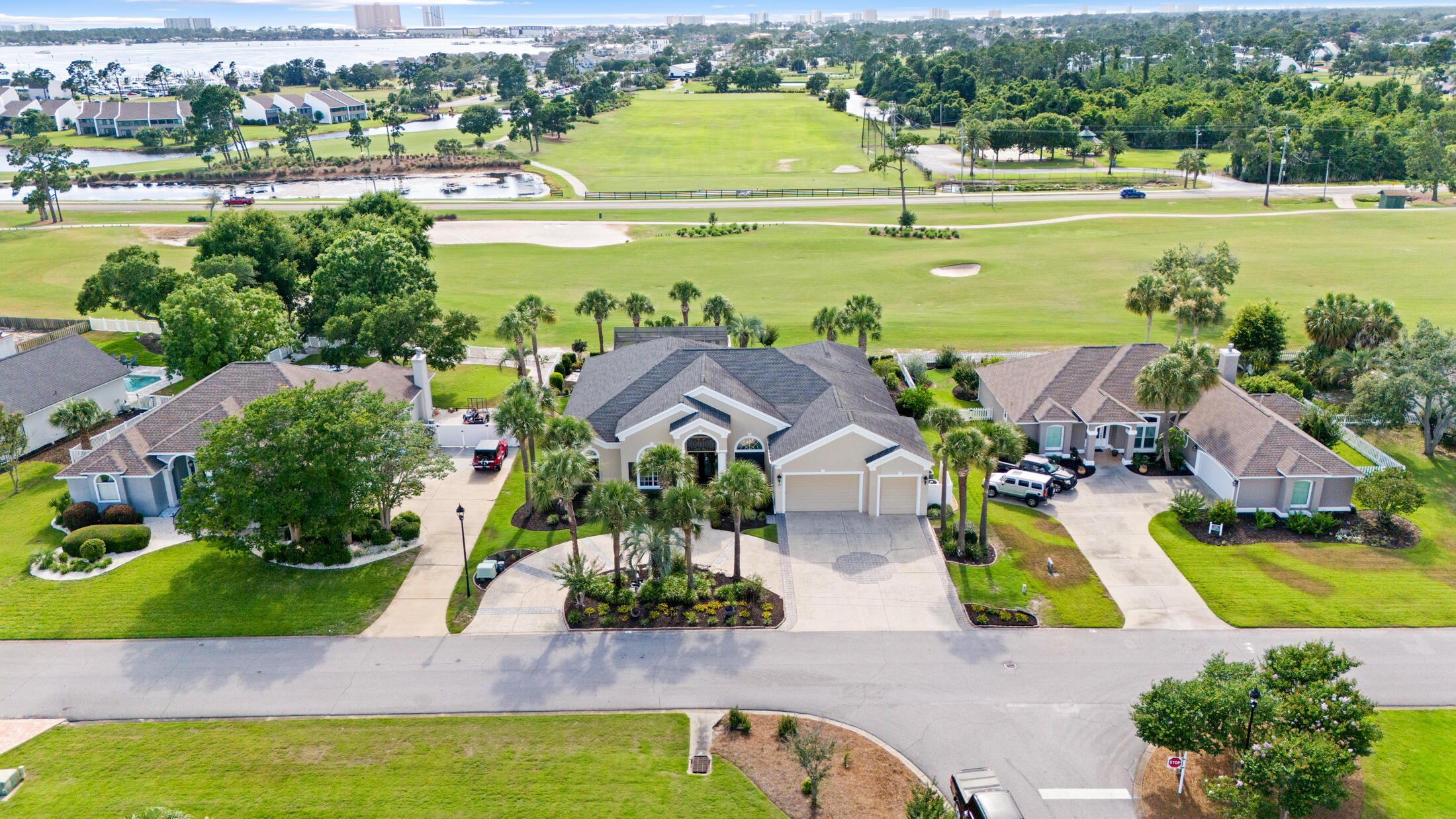 Designed for refined golf course living, this 4-bedroom, 3.5-bath Bay Point home pairs custom architectural details with exceptional indoor-outdoor entertaining spaces. The entry makes an immediate impression with 8ft mahogany doors and a 17ft barrel ceiling painted by a local artist. The living and dining areas feature 15ft ceilings and extensive crown molding. The rest of the home features 12ft ceilings and custom closets in each bedroom all uniquely designed with their own charm including automatic lighting, complemented by custom blinds and drapery in each. French doors lead you to the primary suite with lush new carpet, tray ceiling, and absolute comfort. The master bath has a large Jacuzzi tub, shower for two, an electric fireplace, television, and marble flooring that leads you to a custom walk in closet to dream about. It features a center island, custom storage, automatic and decorative lighting. New high end carpet has also been installed in the large open living room which also has a fireplace and is perfect for entertaining with the wet bar off to the side. The kitchen is equipped with a Thermador 5-burner gas cooktop, Bosch dishwasher, 2016 GE double ovens and microwave, and upper and under-cabinet lighting for added function and ambiance. This kitchen is a hostess' inspiration with an abundance of natural light. The garage has been newly painted, and the attic above is spray-foam insulated. Exterior features include rubber mulch in the garden areas for long-term durability and privacy hedges positioned along the golf course. The outdoor room and pool house are designed for year-round use and include porcelain plank tile, a wood ceiling, stone accent wall, televisions, speakers, a 6ft electric fireplace, wet bar with marble countertop and glass backsplash, and sliding doors that fully open the indoor and outdoor living areas. The pool deck is finished with shell stone tile and includes a gas ceramic fire pit. A private putting green provides space to sharpen your game before heading out for 18 holes on the Nicklaus Course. After golf, stroll the docks at the new Point South Marina or dine at Neon's Bar 72, featuring nightly specials and live music.