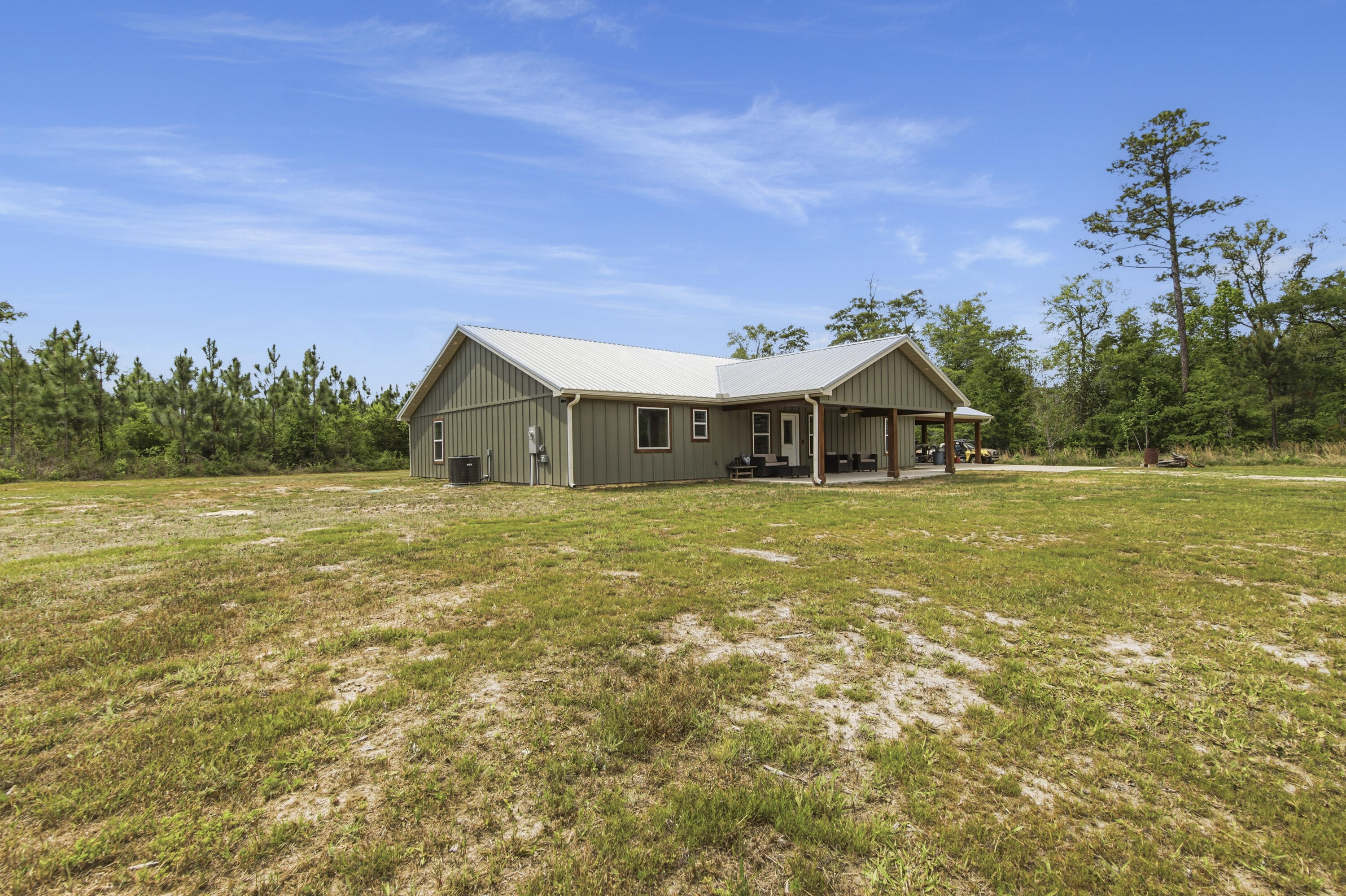 Custom-built Country home on 11.3 acres. 3/3 beauty offers 2400 sqft of heated and cooled living space and 4032 sqft under roof perfect for family gatherings. Home welcomes you with a large covered front porch and enters into a grand open living/kitchen combo with vaulted ceilings covered in poplar wood. Living room offers custom built ins centered around a fireplace, kitchen features a farmhouse sink, bar that sits up to 10 people, built-in oven and microwave combo, gas range, and custom cabinetry. MBR is covered with poplar wood as well, offers his and her closets, double vanities in BA, custom tile shower and large soaker tub. Spray-foamed ceilings and batten insulation keep energy cost low.  Outside a 50-amp RV hookup, carport, and large covered back porch,