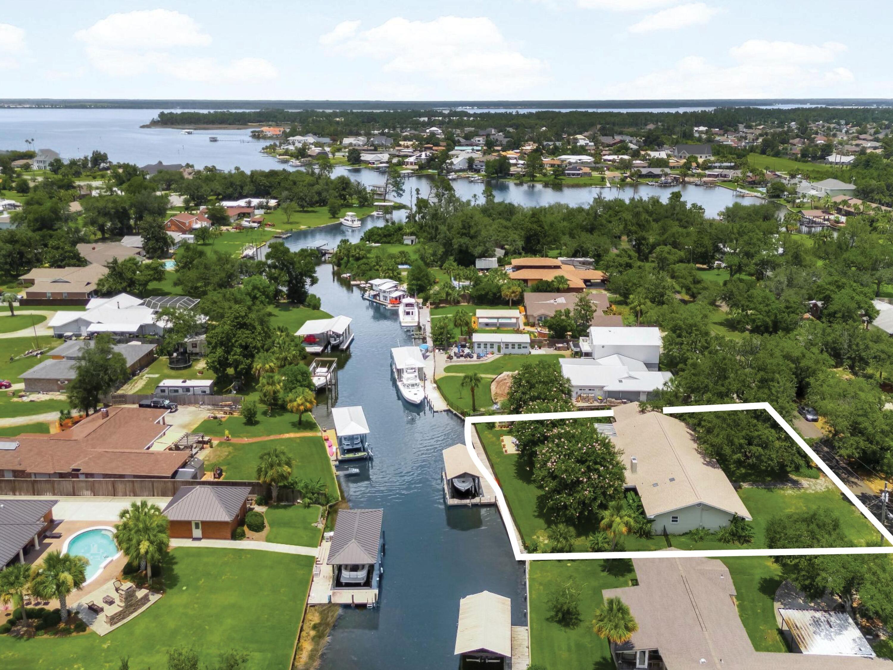Positioned along a deep-water canal on a quiet dead-end, oak-canopied street, 4439 Vista Lane offers a relaxed waterfront setting designed for both everyday comfort and life on the water. Located in the desirable Northshore area of Lynn Haven, free from HOA restrictions, this three-bedroom, two-bath residence spans approximately 2,505 square feet and offers generous interior living space with direct boating access. The home's canal frontage is a defining feature, allowing you to step outside and head straight onto the water. A seawall replaced in 2022 and boat lift motors newly installed in 2025 within a covered boathouse enhance the property's functionality, making it easy to launch a boat and spend the day exploring the surrounding waterways, cruising toward Shell Island, or venturing out into the Gulf. The peaceful canal setting also creates an inviting backdrop for outdoor relaxation, whether enjoying morning coffee by the water or unwinding in the evening with a coastal breeze. A fully fenced backyard adds both privacy and practicality, ideal for pets, gatherings, or simply enjoying the outdoor space. Inside, the residence offers a spacious layout with flexible living areas suited for both quiet evenings and lively gatherings. Multiple living spaces allow for comfortable day-to-day living while providing room to entertain family and friends. Large windows invite natural light throughout the interior, reinforcing the home's open and airy atmosphere. Several major system improvements add long-term confidence for the next owner. The roof and windows were replaced in 2019, while essential infrastructure, including the septic tank, drain field, lift station, and well, was updated in 2016. These thoughtful updates enhance the home's functionality and durability while supporting a low-maintenance waterfront lifestyle. The property's location further enhances its appeal. Set within the established Northshore area of Lynn Haven, the home enjoys a sense of privacy while remaining close to everyday conveniences, top-ranking schools, local dining, and shopping. Lynn Haven itself is one of the most sought-after residential communities in Bay County, valued for its strong sense of community, parks, and access to the water. From this location, residents are just a short drive from the white sand beaches of Panama City Beach while still enjoying the quieter pace of a residential coastal town. With nearby marinas, boat ramps, restaurants, and retail centers, the area offers an ideal balance between waterfront recreation and everyday convenience.