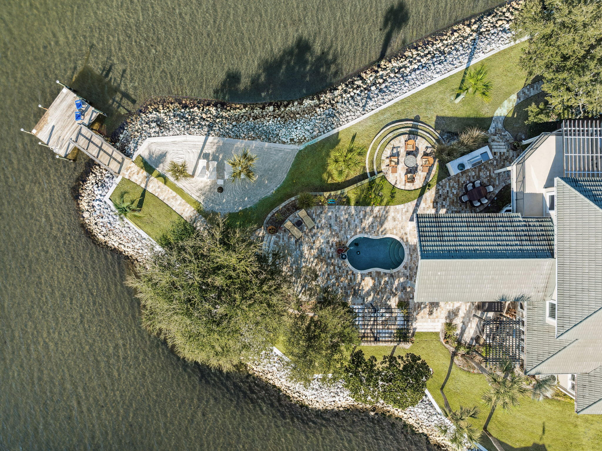 Commanding one of the most extraordinary waterfront positions along the Emerald Coast, Santa Rosa Point occupies its own private peninsula with approximately 500 feet of wraparound frontage on Choctawhatchee Bay. Set on more than an acre of secluded, meticulously landscaped grounds, the estate is surrounded by water on three sides, offering a rare sense of privacy and natural beauty that feels removed yet remains remarkably connected. This is one of just a few deepwater locations on the bay, making it ideal for boating and water enthusiasts. Mornings begin with soft eastern light and dolphins gliding through the bay, while evenings bring sweeping sunsets as herons, osprey, and pelicans return home.
The grounds are richly landscaped with mature tropical plantings and an abundance of palm trees that enhance the property's coastal setting. Along the shoreline, a private manmade white sandy beach provides a rare and inviting waterfront retreat, perfect for relaxing or enjoying the calm bay waters.

Designed for both refined entertaining and effortless daily living, the residence features expansive interior spaces oriented toward uninterrupted water views. The main living areas and primary suite sit just steps from the shoreline, allowing the bay to shape everyday life. The owner's retreat serves as a private sanctuary, featuring a spa-inspired bath with a steam shower and body sprayers, generous walk-in closets with secure storage, and direct access to outdoor living areas overlooking the water.

Solid hardwood flooring in the primary living spaces is complemented by travertine accents and carefully selected low-glare lighting, creating a warm and refined ambiance throughout. The kitchen balances elegance and functionality with custom cabinetry, a Wolf range and oven, and a Sub-Zero refrigerator freezer, supported by an additional full-sized refrigerator in the laundry room.

Five bedrooms are thoughtfully arranged for privacy and flexibility, including two suites on the main level and additional bedrooms with Jack-and-Jill and ensuite-style baths. A dedicated office or workout room and an elevated deck provide inspiring bay views for work, wellness, or quiet retreat.

Abundant storage is found throughout the home, enhanced by custom cabinetry and slat-wall systems in the garage. Four insulated garage bays--one configured as a relaxed man cave--offer ample room for vehicles and recreational gear.

Built with resilience as a priority, the residence features metal stud construction, thick stucco-covered concrete walls, metal trusses, a metal roof, and hurricane-rated windows. A geothermal HVAC system with zoned climate control has been recently upgraded and remains under warranty. A pressure-regulated hot water circulation system ensures rapid delivery throughout the home, while a recently installed whole-house 30kW generator ensures reliable backup power and added peace of mind

Outdoor living rivals that of a private resort with a pool, hot tub, three outdoor showers, an outdoor fireplace and fire pit, expansive patios and balconies, trellis-covered swings, and a shaded daybed retreat. Automated landscape lighting, irrigation, Bluetooth-enabled outdoor speakers, a solar-powered gated entry, and a comprehensive security system provide comfort and peace of mind. Tucked within the wooded portion of the property is a charming kids' "treehouse" style cabana, creating a whimsical hideaway and unique gathering space.

For boating enthusiasts, the estate is anchored by an exceptional dock measuring approximately 58 by 38 feet, equipped with multiple lifts including one rated for up to 20,000 pounds, additional lifts for personal watercraft, and expansive decking designed for both functionality and enjoyment. A separate dock pier at the end of the peninsula provides an additional elevated fishing location, complementing the large boathouse deck and offering several ideal vantage points for casting into the bay. The dock system also includes a swim platform, fish-cleaning station, lighting package, boat power connections, and storage for kayaks and paddleboards, with direct access to both the bay and offshore fishing.

A recreational package is also available for purchase, offering a turnkey coastal lifestyle and including a Pursuit 326 Offshore boat, Yamaha 210 FSH jet boat, Sea-Doo Wake personal watercraft, kayaks, paddleboards, and golf clubs, allowing new owners to immediately enjoy the full range of waterfront and outdoor recreation this exceptional property provides.

The white-sand beaches of Scenic Highway 30A are fabulous and just five minutes away.  But tucked at the end of the road within a small, secluded enclave, Santa Rosa Point offers an escape with more safety, security and privacy for your family, as well as closer proximity to shopping, dining, and entertainment.  It's the best of both worlds!

Meticulously maintained and singular in its setting, this private peninsula estate stands as a true legacy property.