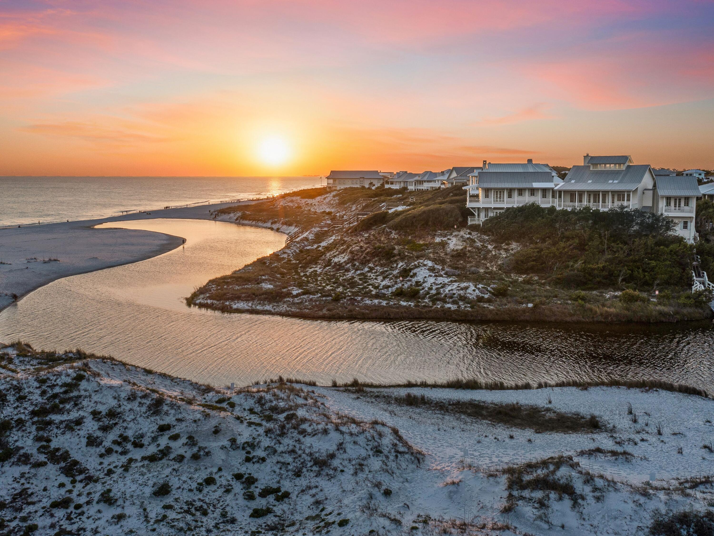 Rare even by 30A standards, this legacy property commands one of the most extraordinary settings on the coast, with Draper Lake and the gulf unfolding in a sweeping panorama that rivals any view along our coastline. This residence was designed to honor its remarkable homesite, pairing enduring construction with architecture that feels both stately and deeply connected to the landscape. From the moment of arrival, the experience is defined by elevation, light and an ever-changing backdrop of dune vegetation, lake outfall and open water. Built in 2006, the five-bedroom residence spans over 4,700 square feet of heated and cooled living space and rests on a homesite with an exceptional 245+ feet of combined waterfrontage. Engineered for longevity, the structure is anchored by deep wood pilings and reinforced by substantial retaining walls, a thoughtful response to its elevated coastal setting. A private elevator, whole-home generator, six-zone HVAC system and smart home integration provide a level of comfort and functionality that quietly supports everyday living. The home's Low Country-inspired architecture is expressed through cedar lap siding, a standing seam metal roof, copper-accented railings and expansive Brazilian hardwood decking. Inside, hand-hewn cypress floors, marble surfaces, tongue-and-groove cypress paneling and exposed cypress trusses create a layered interior rich in texture and craftsmanship. The main living, dining and kitchen spaces are crowned by a dramatic Cathedral ceiling with clerestory light, while walls of windows and French doors frame uninterrupted coastal views. The kitchen is both refined and highly functional, anchored by a statement La Cornue range, Sub-Zero refrigeration, custom cabinetry and a well-appointed butler's pantry. The gulf-facing primary suite opens onto a covered porch and features a beautifully detailed bath and built-in wall of mirrored closet doors. Guest suites are treated equally, each with a private bath and many offering direct access to outdoor living areas. Outdoor spaces are designed to complement the setting without competing with it. A private pool tucked behind native vegetation creates a sense of seclusion, while covered porches and elevated decks offer multiple vantage points to take in the view. A private dock and boardwalk extend to Draper Lake, offering effortless access for paddleboarding, kayaking and quiet mornings on the water. Within the gated community, owners enjoy multiple beach walkovers, a community pool and dedicated beach access. With frontage on both a coastal dune lake and the gulf, this is a unique location and elevation along Scenic Highway 30A.