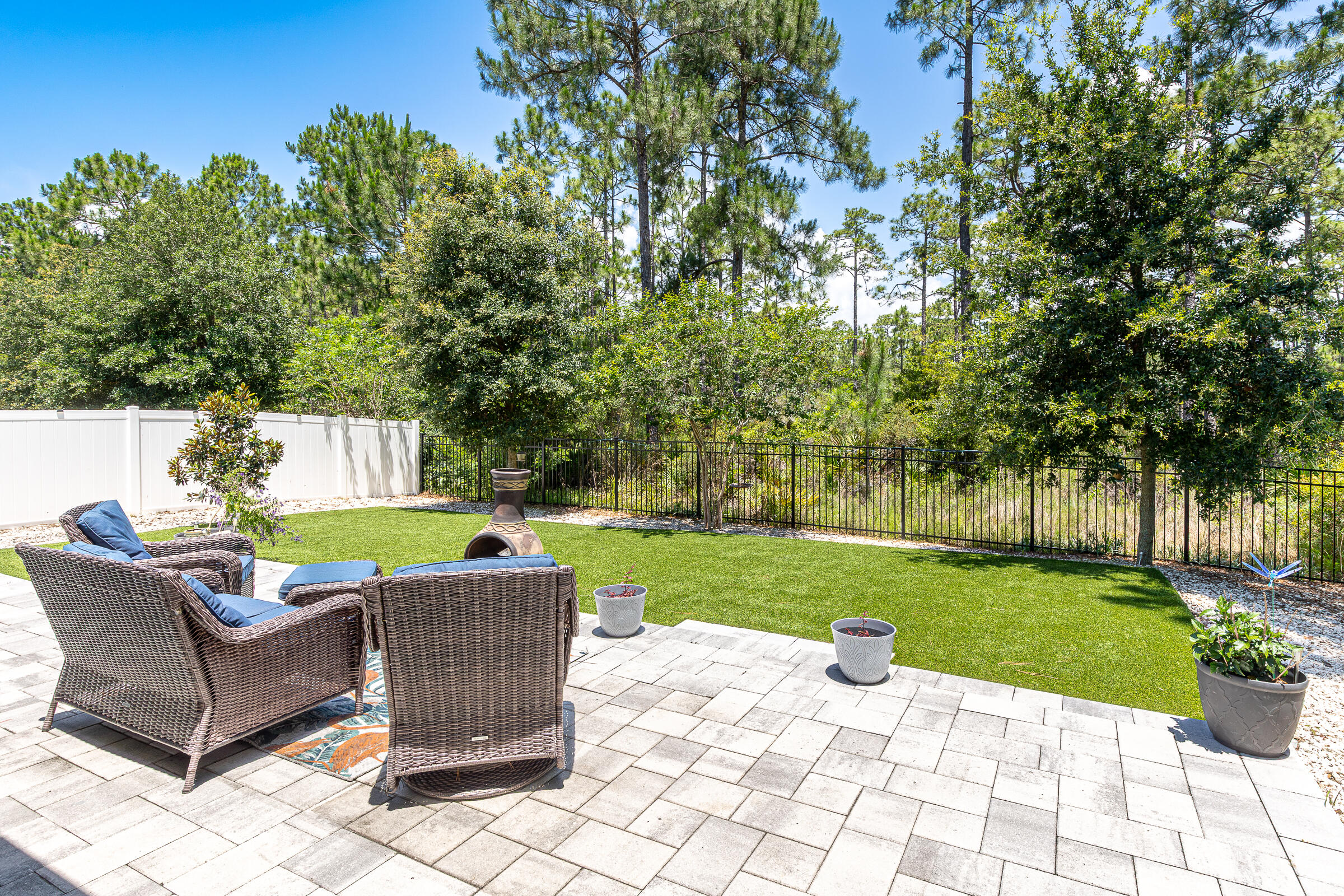 Single-story charmer in Stonegate! Built in 2019, this like-new Bailey floor plan offers Smart Home technology, a versatile flex room, and move-in-ready convenience. Ideally located just minutes from Walmart, Sacred Heart Hospital, Sandestin, Grand Boulevard, 30A beaches, shopping, dining, and entertainment, this home perfectly blends comfort and accessibility.
Perfectly positioned on a corner lot with serene preserve views, this property offers exceptional privacy and beautifully enhanced outdoor living spaces. The inviting front porch is ideal for relaxing with rocking chairs or a porch swing, while the backyard showcases extensive hardscape improvements, including a spacious extended paver patio, decorative rock beds, artificial turf, and black wrought-iron fencing. Thoughtfully designed for minimal upkeep and maximum enjoyment, this outdoor oasis provides the perfect setting for entertaining or unwinding year-round.
Inside, the open-concept layout creates a bright and spacious feel, centered around a well-appointed kitchen featuring granite countertops, stainless steel appliances, gray cabinetry, a center island, and a casual dining area overlooking the oversized family room with tray ceiling. The desirable split-bedroom floor plan places the primary suite privately at the rear of the home, complete with dual vanities, a soaking tub, separate shower, and walk-in closet. Two additional bedrooms, both with walk-in closets, share a full bath on the opposite side of the home.