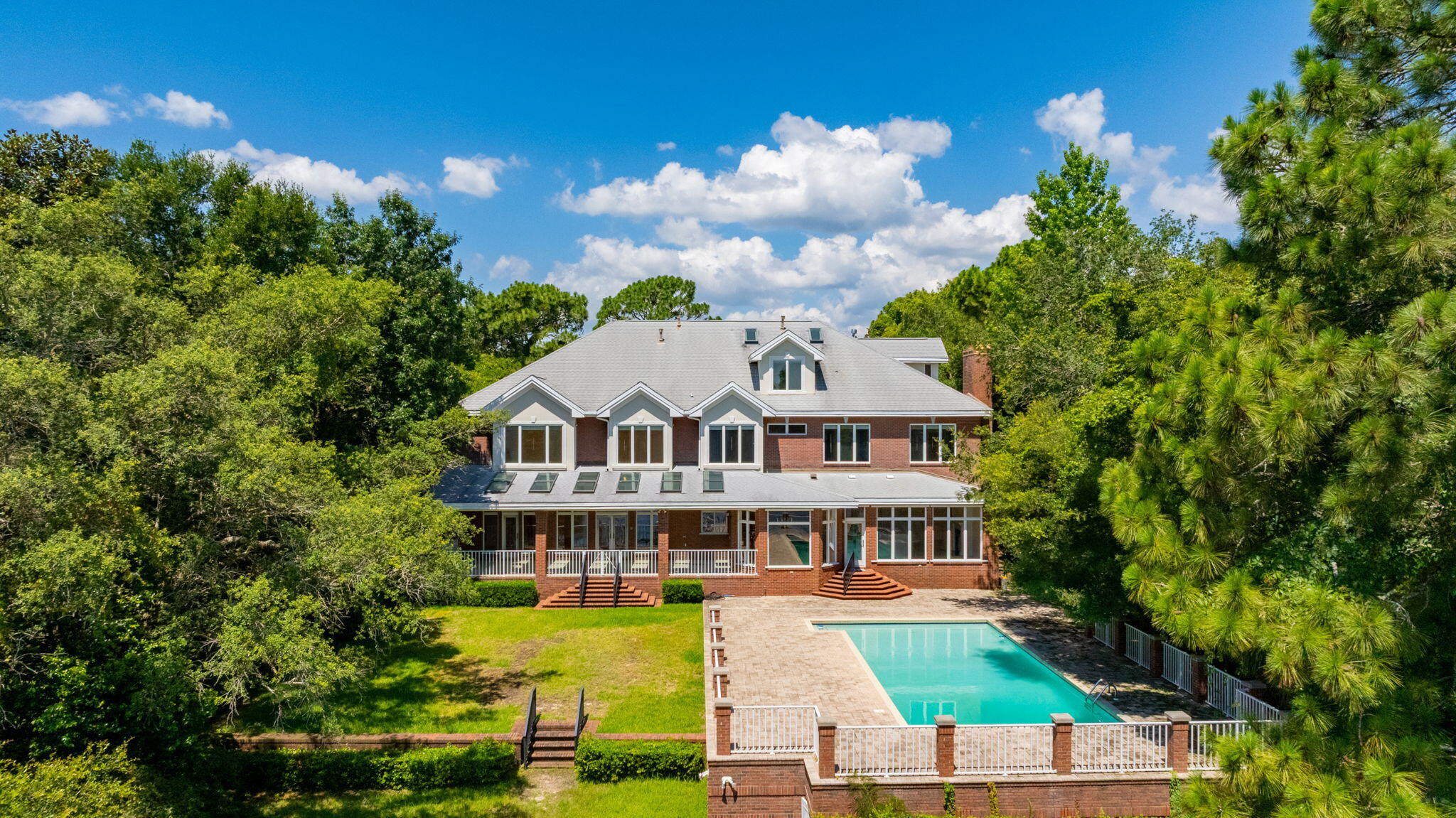 Experience exceptional waterfront living with over 100 feet of frontage and deep water access on Poquito Bayou.  Situated on a beautifully elevated lot with a private driveway, this impressive brick estate offers over 8,000 square feet of living space, 6 bedrooms, 7 full bathrooms, and an oversized four-car garage.  Designed for both entertaining and everyday living, the outdoor oasis features a sparkling resurfaced pool surrounded by an expansive patio with updated pavers, creating the perfect setting for relaxing or hosting family and friends. Inside, the chef's kitchen is equipped with custom cherry cabinetry, granite countertops, a Viking gas range, and Sub-Zero refrigerator and freezer.  Marble flooring welcomes you through the grand foyer and kitchen, while rich hardwood floors extend throughout the library, living room, and dining room. The stunning library showcases floor-to-ceiling custom cherry built-in bookcases, creating a warm and inviting retreat. Additional highlights include a spacious laundry room, oversized pantry, generous bathrooms, and abundant storage throughout.  Soaring 10-foot ceilings on both levels, transom windows, and an abundance of natural light enhance the home's timeless elegance. Water views from most rooms provide a peaceful backdrop, making this extraordinary bayfront residence the perfect blend of luxury, comfort, and coastal living.  New Roof in 2011; Generator Installed in 2021 and new HVAC in May, 2026.
