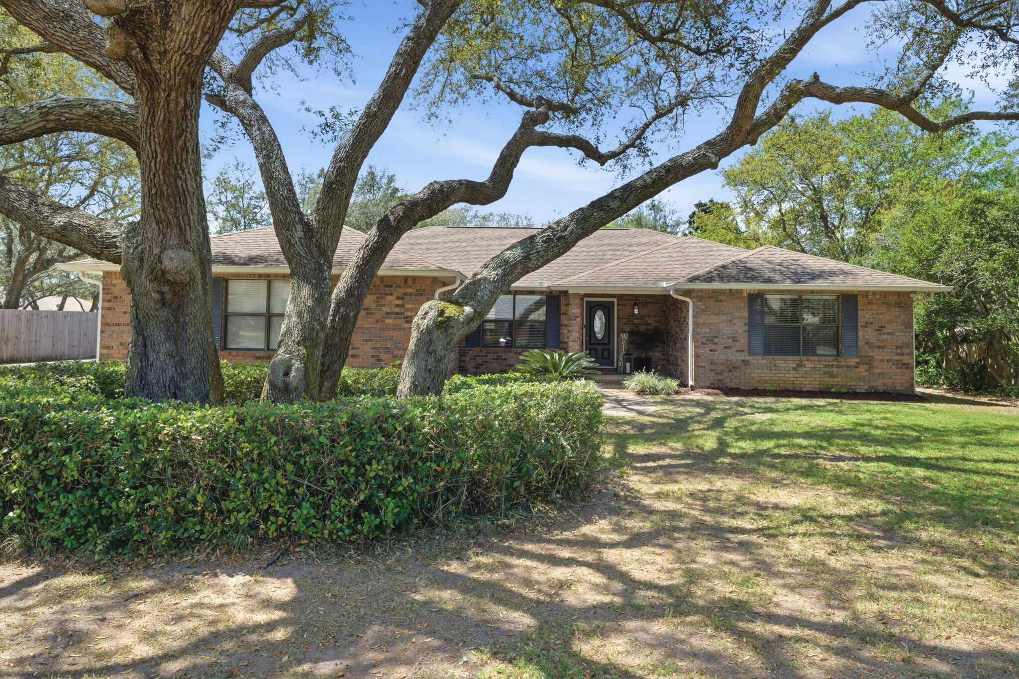 🏠 YOUR HOLLEY BY THE SEA OASIS AWAITS! 🌴Seller open to replacing the roof prior to closing!   Welcome to your dream home nestled in the heart of one of Navarre's most highly sought-after neighborhoods. Perfectly positioned just steps from the lush greens of the Hidden Creek Golf Course, this charming brick beauty sits on an expansive, nearly half-acre lot (0.46acres). From the gorgeous mature shade trees out front to the private backyard retreat, this property effortlessly blends classic coastal charm with modern living.  ✨ PROPERTY HIGHLIGHTS ✨Space to Move: Enjoy over 2,000 SqFt of perfectly designed living space featuring a highly desirable split floor plan and an open-concept main living area.  Chef's Delight: The updated kitchen boasts stunning granite countertops, a breakfast bar, sleek tile backsplash, a bright breakfast nook with a bay window looking out to the yard, and a full suite of stainless steel and black appliances.  Versatile Living: Just off the entry sits a flexible space perfect for a formal dining room, a home office, or a cozy library.  Primary Suite Retreat: The spacious master bedroom features an en-suite bath complete with a garden tub, separate shower, double vanity, and a massive walk-in closet.  Outdoor Paradise: A fully fenced backyard features a double-gate entry, perfect for boat or RV storage. Relax or entertain rain or shine on your massive screened porch!  Parking & Storage: An extended driveway leads to a side-entry 2 car garage. RESORT-STYLE AMENITIES - As part of the Holley By The Sea community, you gain exclusive access to a multi-million dollar recreation facility! Your low annual assessment covers:  Multiple community pools   Lighted tennis courts & a fully equipped fitness center/sauna   A playground, game room, and community room   Deeded water access, picnic pavilions, and more!  BUYER BONUS: Peace of mind comes standard here. Bring us a great offer, and the sellers are willing to replace the roof before you close!