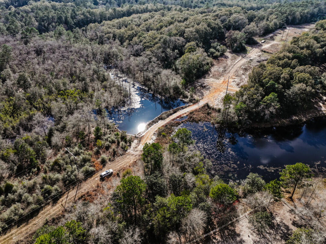Rare opportunity to own 94+/- pristine acres of natural beauty and complete privacy. This expansive acreage offers the perfect canvas for a luxury private estate, a family legacy compound, or a premier recreational retreat. The centerpiece of the property is a stunning, large spring-fed pond that serves as a focal point for the landscape. A newly created access point across the water provides seamless entry to the back 80 acres, opening up the full potential of the land for building sites or trail systems. Bridge Creek also provides a natural water source flowing through the north of the larger back parcel. Located just 5 minutes from downtown DeFuniak Springs and only 10 minutes from I-10, this property offers the ultimate 'best of both worlds': total seclusion with rapid access to local amenities and major travel routes. The land is characterized by a stunning, diverse canopy of majestic oaks and mature hardwoods. Unlike many large tracts in the area, this property consists of natural growth, not planted pines, providing a timeless, established feel and a high-quality ecosystem for local wildlife. Whether you are looking to build your dream home surrounded by nature or seeking a significant land investment, this property offers a unique combination of scale, water features, and untouched beauty.