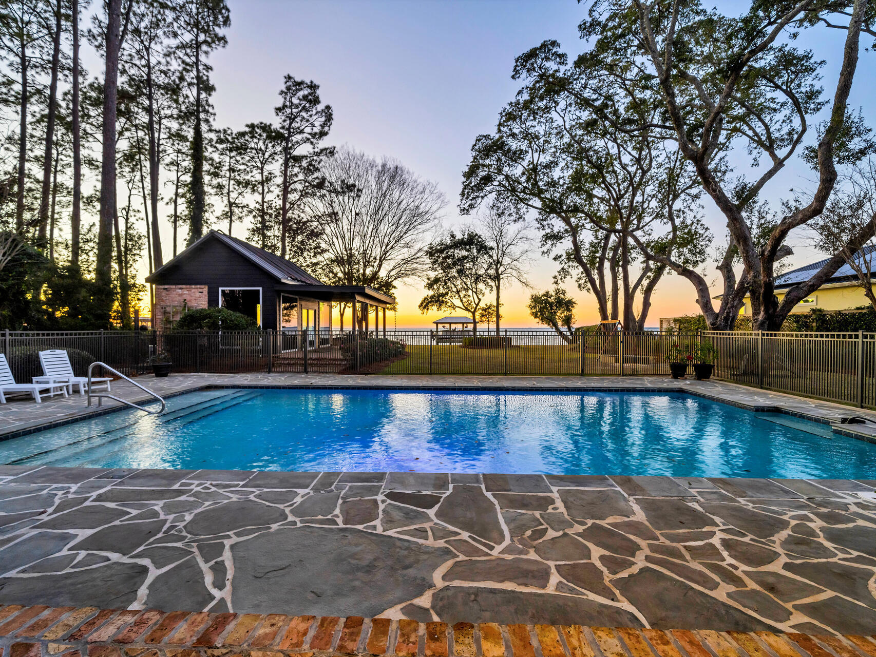Watch the sun sink into the bay from this custom-designed, majestic waterfront estate on a sprawling 1.1 acres with dockage, spacious pool and plenty of room for indoor and outdoor entertaining. From the long circular drive to the charming central courtyard ringed with balconies, this 7,401 sf home embraces your family and friends with the warm and welcoming spirit of New Orleans. While space abounds, the 7 bed/5 full bath/2 half bath compound is comfortably divided into a two-wing main home, separate carriage house with an efficiency apartment, expansive pool deck with brick fire pit, and a fun summer kitchen/man cave with the cozy atmosphere of a local bar and grill. The main home wows your guests with a dramatic front entrance, antique doors, copper gutters and stunning old Chicago brick accents while old-fashioned Southern charm invites them to stay with brick interior archways, outdoor alcoves for reading or relaxing, plus private covered balconies and porches tucked in throughout the design. The main house gourmet kitchen is outfitted with a new Subzero refrigerator, two Bosch dishwashers, Jenn-Aire cooktop, wine coolers, warming drawer and an oversized L-shaped granite island. The adjoining dining room includes the convenience of a built-in custom buffet with warming drawer.  The primary bedroom is on the ground floor with open bay views, soaring ceiling, separate sitting area and a stunning primary bath with a surprise private garden. Upstairs are two more bedrooms and full baths, and a recently updated media room/gym/bonus room.  

The separate two story guest wing adds 3 more bedrooms, 2 full baths and a separate full kitchen.  The estate also offers the advantage of two laundry areas.

Outside is a substantial backyard and a huge 20 x 40 pool trimmed in Tennessee bluestone. The bayfront dock includes two boat lifts, a boat house, jet ski lift, kayak platform and flow-through decking for longevity.  The main house and guest annex also have a new metal roof. Driftwood Estates is located down Mack Bayou near Sacred Heart Hospital, A+ rated public schools, Grand Boulevard for dining and shopping, and is just minutes from 30A beaches. Call today to schedule your private visit to this one-of-a-kind estate.
