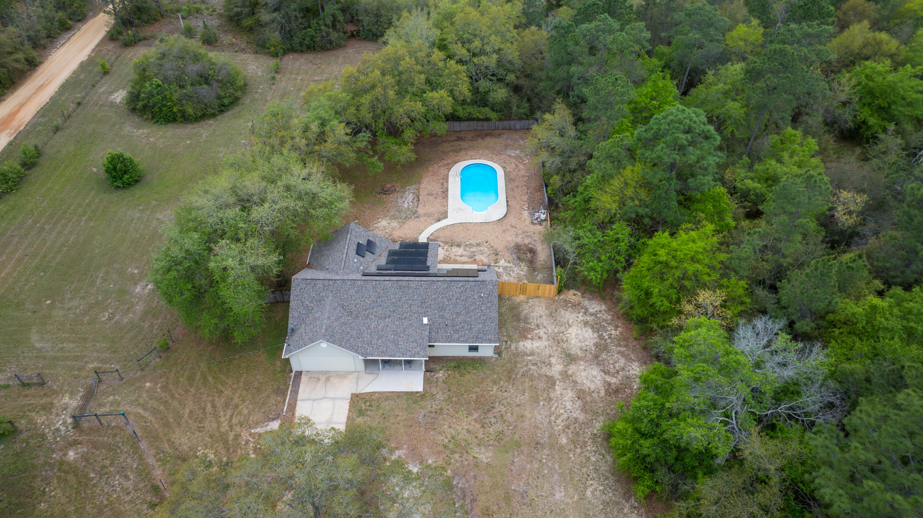 Experience the perfect blend of country charm and modern convenience at this exceptional property. Nestled on 3.84 acres, this home offers plenty of room to spread out while still being close to everything you need. Located just minutes from the Ray Lynn Barnes Boat Ramp, you'll have quick access to the Shoal River for boating and outdoor recreation. Commuters will appreciate the easy access to Interstate 10 and close proximity to town. Inside, you'll find a thoughtfully designed open-concept layout with wood-look tile flooring throughout the main living spaces and a split-bedroom floor plan for added privacy. The kitchen is the heart of the home, featuring granite countertops, stainless steel appliances, and a large island with bar seating ideal for gatherings and everyday living. A fresh coat of paint gives the kitchen a bright, updated feel. Enjoy year-round relaxation in the enclosed Florida room overlooking your private backyard retreat, complete with a large in-ground chlorine pool. Need extra space? A finished loft and enclosed garage provide the perfect bonus areas for a playroom, office, or guest space. The primary suite is designed for comfort, featuring a spacious walk-in closet, dual vanities, a glass-enclosed walk-in shower, and a soothing whirlpool tub. Outdoors, the possibilities are endless. The property includes a fenced corral ready for livestock and a privacy-fenced yard with a new double gate which is perfect for securely storing a boat or RV. A 2021 roof replacement adds lasting value and peace of mind. If you've been searching for space, versatility, and a touch of Florida lifestyle, this one checks all the boxes.