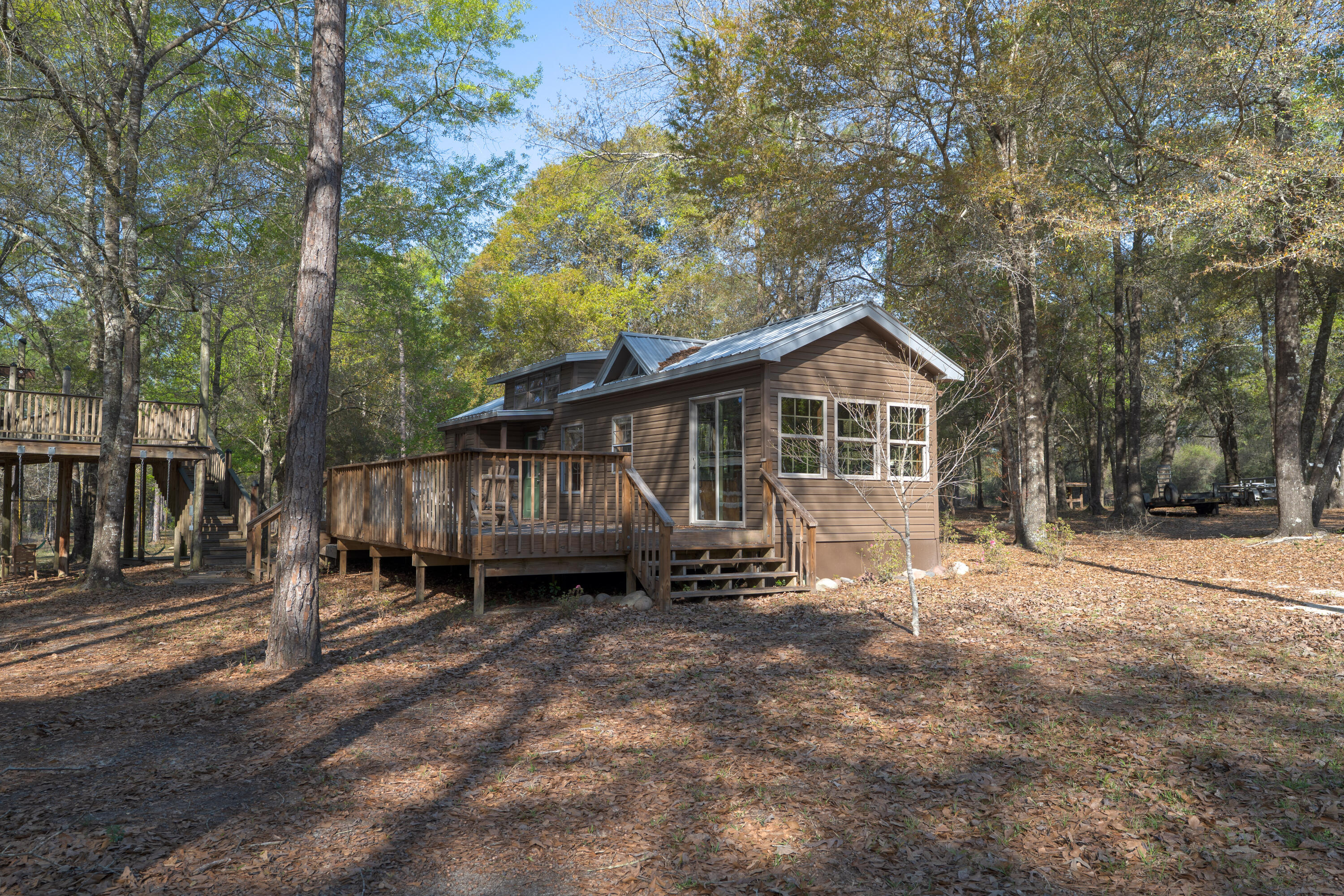 Turn-key retreat complete with utilities, cabin, massive metal garage, outdoor kitchen, Fireplace, 300 fruit trees, irrigation, 300' zip-line, ATV trail, and more! Cabin 2013, new roof with added overhangs 2020. Primary bedroom downstairs with a loft upstairs. Full bath inside with extra half bath on the deck. Septic system oversized for future expansion, with RV septic and electric hookups. 500 gal underground propane tank. Over 300 fruit trees including, Blueberries, Apples, Peaches, Plums, and many more. Walton plantation is a private gated community. Owners enjoy 2500 shared acres including a communal garden, chapel, fishing pond, Horse and ATV riding trails, and 300 yds of shooting ranges. Join the hunting club for access to 2000 acres of beautiful lan