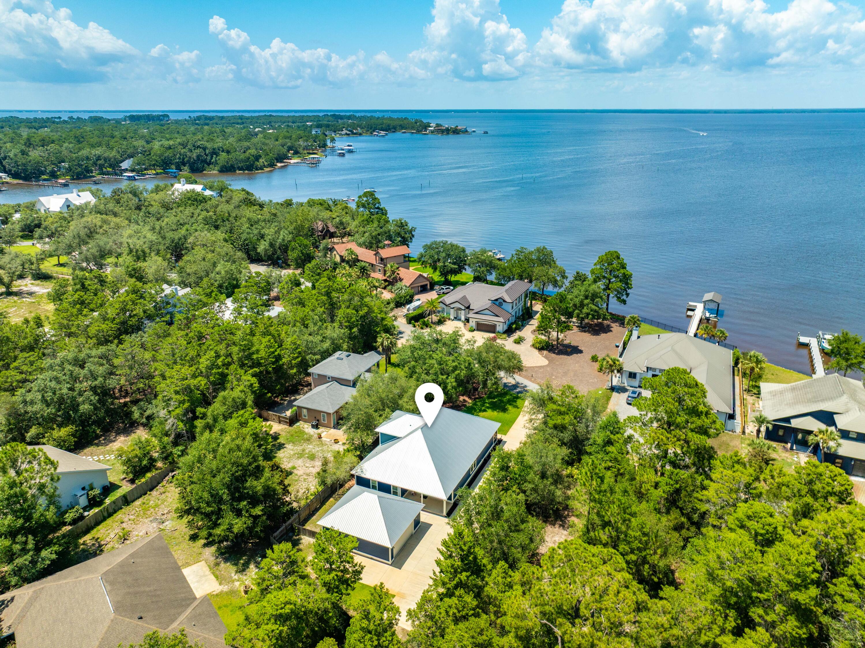 Thoughtfully designed around comfort, functionality, and its exceptional bayside setting, this custom-built 5-bedroom, 3-bath residence is perfectly positioned directly across from Choctawhatchee Bay in the gated community of Pelican Bay and offers 3,956 square feet of thoughtfully designed indoor/outdoor living and entertaining space, including 2,162 square feet of heated and cooled living area. Framed by mature landscaping and highlighted by a spacious screened front porch with peaceful bay views, the home offers an exceptionally functional floor plan with nearly every aspect of daily living on the first floor, including the open-concept living, dining, and kitchen areas, the primary suite, three additional bedrooms, and two full baths, while the upstairs bedroom/flex space with a full bath provides exceptional versatility for guests, a home office, media room, or additional living space. Built with lasting quality in mind, the home showcases custom craftsmanship throughout with built-ins, tray ceilings, shaker-style cabinetry, granite countertops, abundant storage, a Rinnai tankless water heater, whole-house Generac generator, oversized two-car garage, long driveway, and a spacious backyard with ample room for gardening, recreation, or future outdoor enhancements including a pool. Whether you're searching for a primary residence, second home, or investment opportunity, this exceptional home offers the ideal blend of comfort, functionality, and location. Pelican Bay offers a peaceful coastal setting with low HOA fees, a bayfront park with community dock for fishing, kayaking, paddleboarding, and boating, along with tennis and pickleball courts. Ideally located just minutes from Grand Boulevard, Sacred Heart Hospital, Sandestin, Topsail Hill Preserve State Park, Scenic Highway 30A, and the Emerald Coast's renowned sugar-white beaches, this home offers the perfect balance of quiet coastal living and convenient access to the area's premier shopping, dining, entertainment, and outdoor recreation.