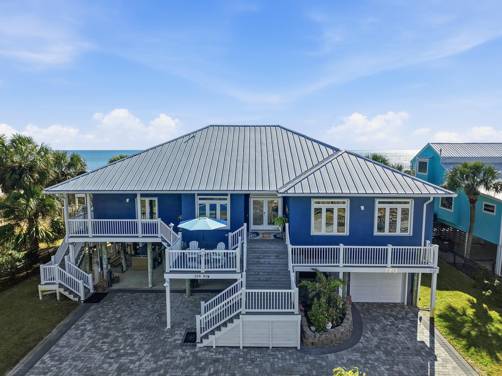 Rare Gulf Front Home-Old Florida Privacy. Welcome to 170 Gulf Pines Dr in Port St. Joe, FL, an exceptional coastal home offering relaxed Gulf living just steps from the sugar-white sands of the Gulf of America. This beautifully maintained residence features 5 bedrooms, 4 full bathrooms, and 2 half bath across 2,677 square feet of living space, making it ideal as a primary residence, second home, or vacation rental investment. The home's striking coastal exterior, durable metal roof, and elevated design are showcased in the photos and drone footage. Expansive covered porches provide inviting spaces to enjoy Gulf breezes, morning coffee, and evening sunsets, with peaceful views of the surrounding neighborhood and glimpses of the water. Inside, the spacious layout is designed for comfort and functionality, offering ample room for family and guests. The elevated construction enhances natural light and airflow, while the generous bedroom and bathroom configuration provides privacy and flexibility for entertaining. A large custom "Container Store" pantry gives one more ease of daily needs. The exceptional front-yard outdoor living area, thoughtfully designed into a private, resort-style oasis. The screened-in pool enclosure creates an open, airy atmosphere while providing shade and comfort, allowing the pool to be enjoyed year-round. Surrounding deck space offers plenty of room for lounging or entertaining. Beneath the home, a ground-level screened-in living/entertainment area provides a shaded, breezy retreat ideal for outdoor dining, relaxing, or gathering with friends and family after a day at the beach. Easy access to the pool and front yard enhances the home's seamless indoor-outdoor flow. Add'l features include a garage, ground-level storage for beach gear and water toys, and generous paved parking. Located in the desirable Gulf Pines community, this home offers easy access to downtown Port St. Joe, dining, shopping, boating, and miles of pristine Gulf beaches.