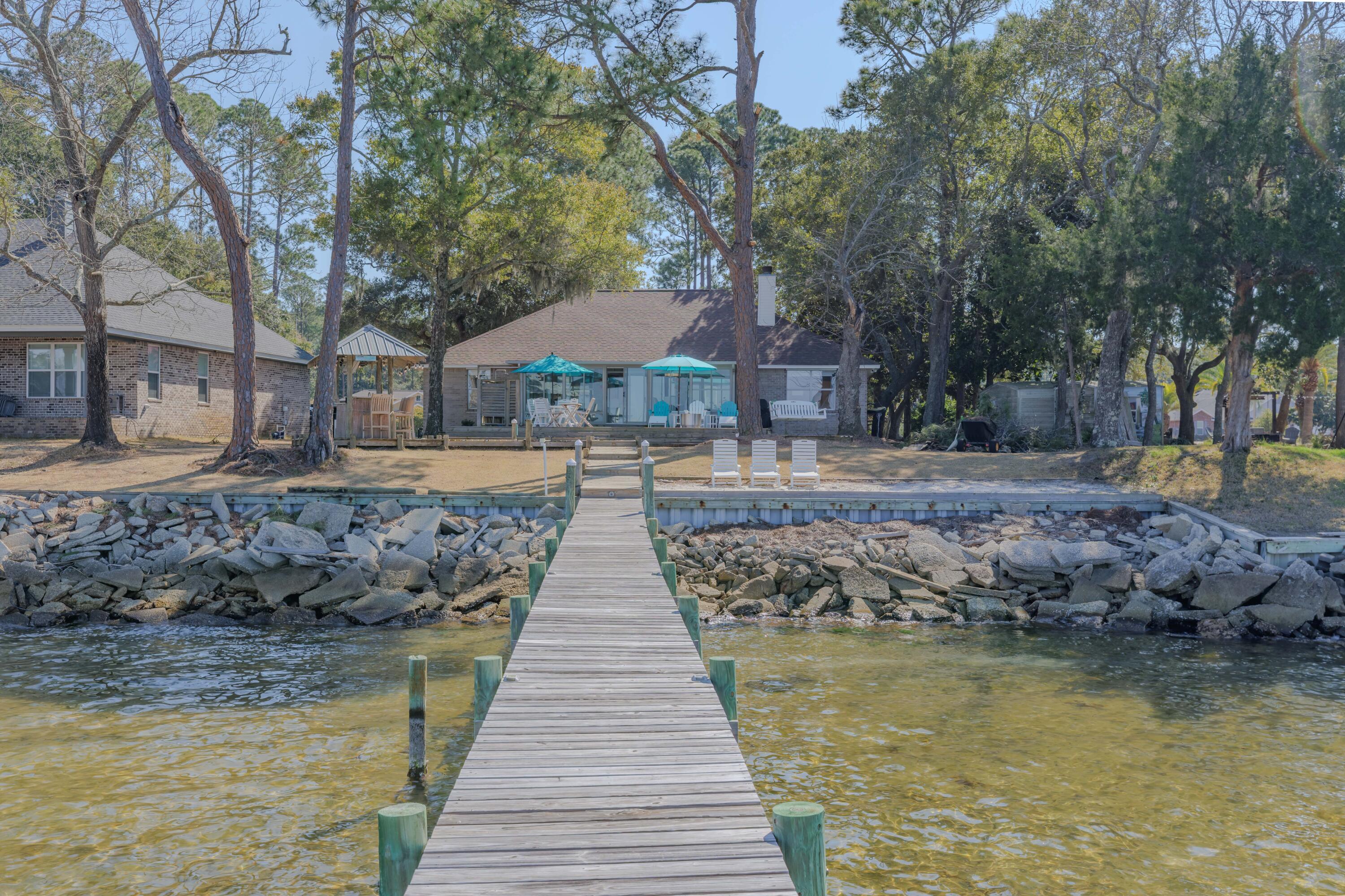 Wake up to panoramic East Bay waterfront views in this elevated 'X' Flood Zone' coastal retreat. Direct bay frontage, majestic oak trees, and breathtaking sunsets create an exceptional waterfront setting that defines true coastal living. This beautifully maintained one-story home offers an elevated homesite and peaceful natural surroundings. Inside, the desirable open floor plan provides seamless flow for both everyday living and entertaining. Natural light fills the spacious interior, highlighting the inviting living room anchored by a handsome fireplace centerpiece that adds architectural interest and warmth. Generous bedrooms provide comfort and privacy, while the Florida room offers a front-row seat to sweeping bay views and vibrant sunset skies throughout the year.